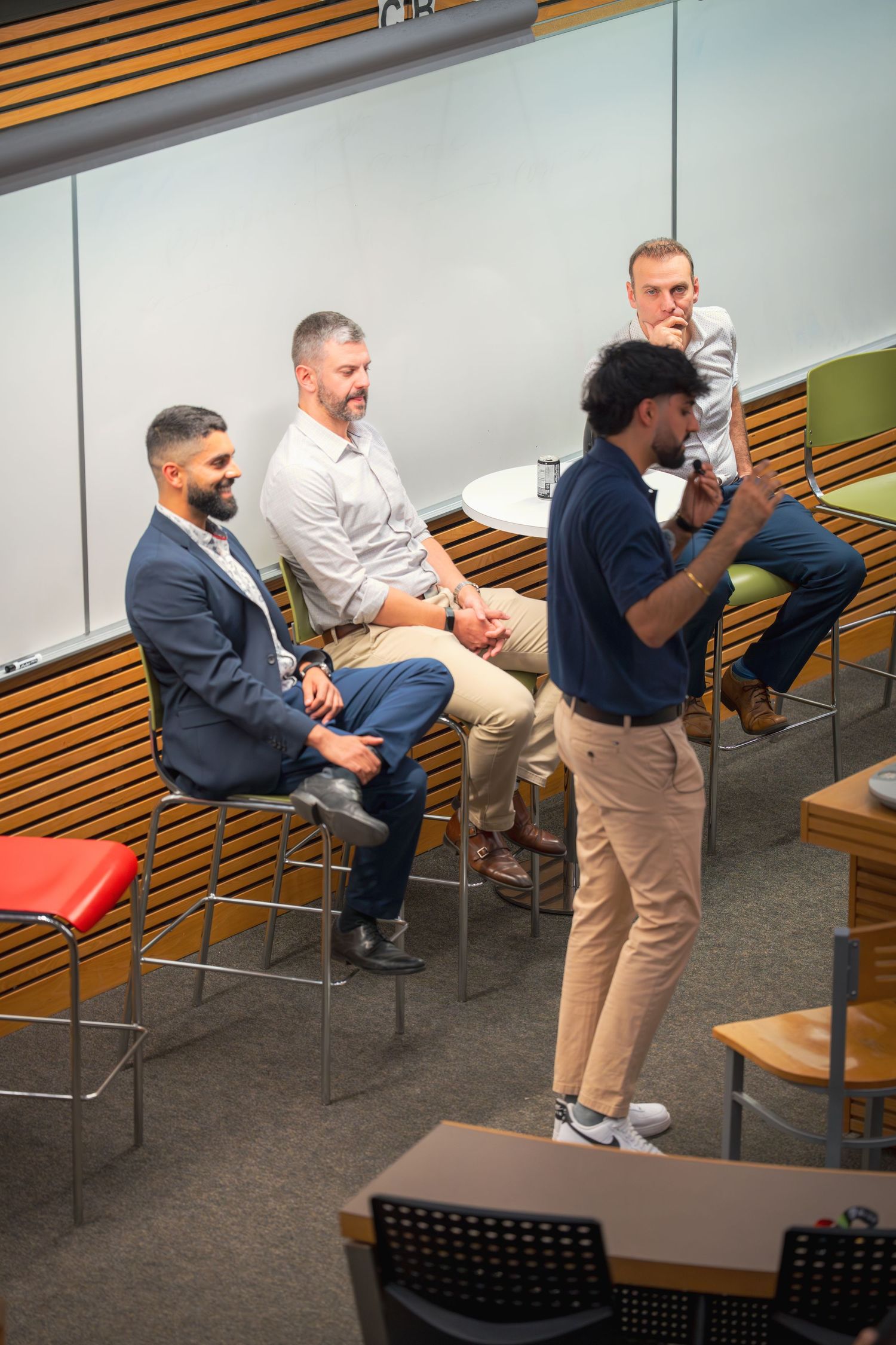 Group discussion in modern lecture hall with wooden accents and tiered seating.