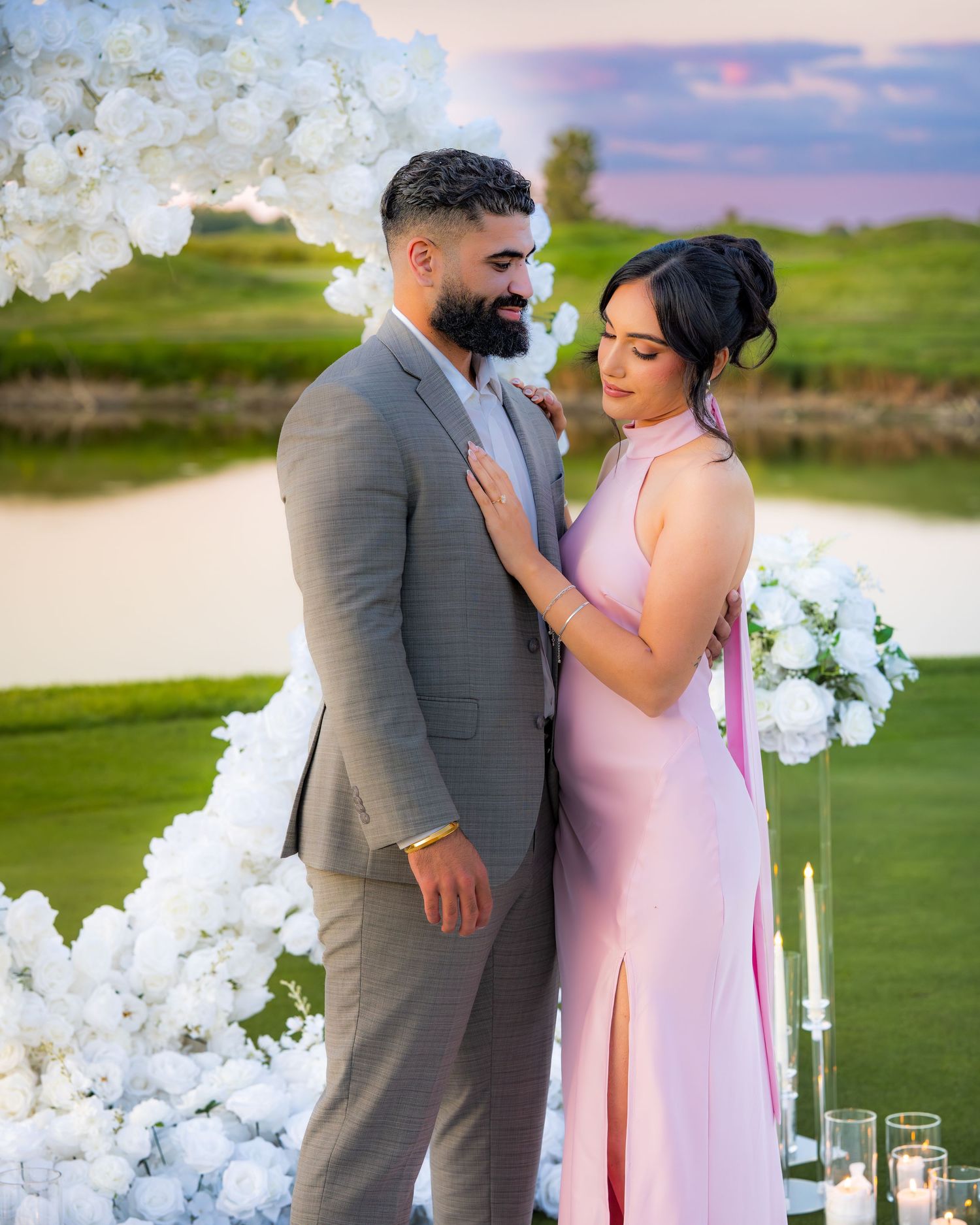 A couple embraces during their outdoor photoshoot with elegant white floral decorations.