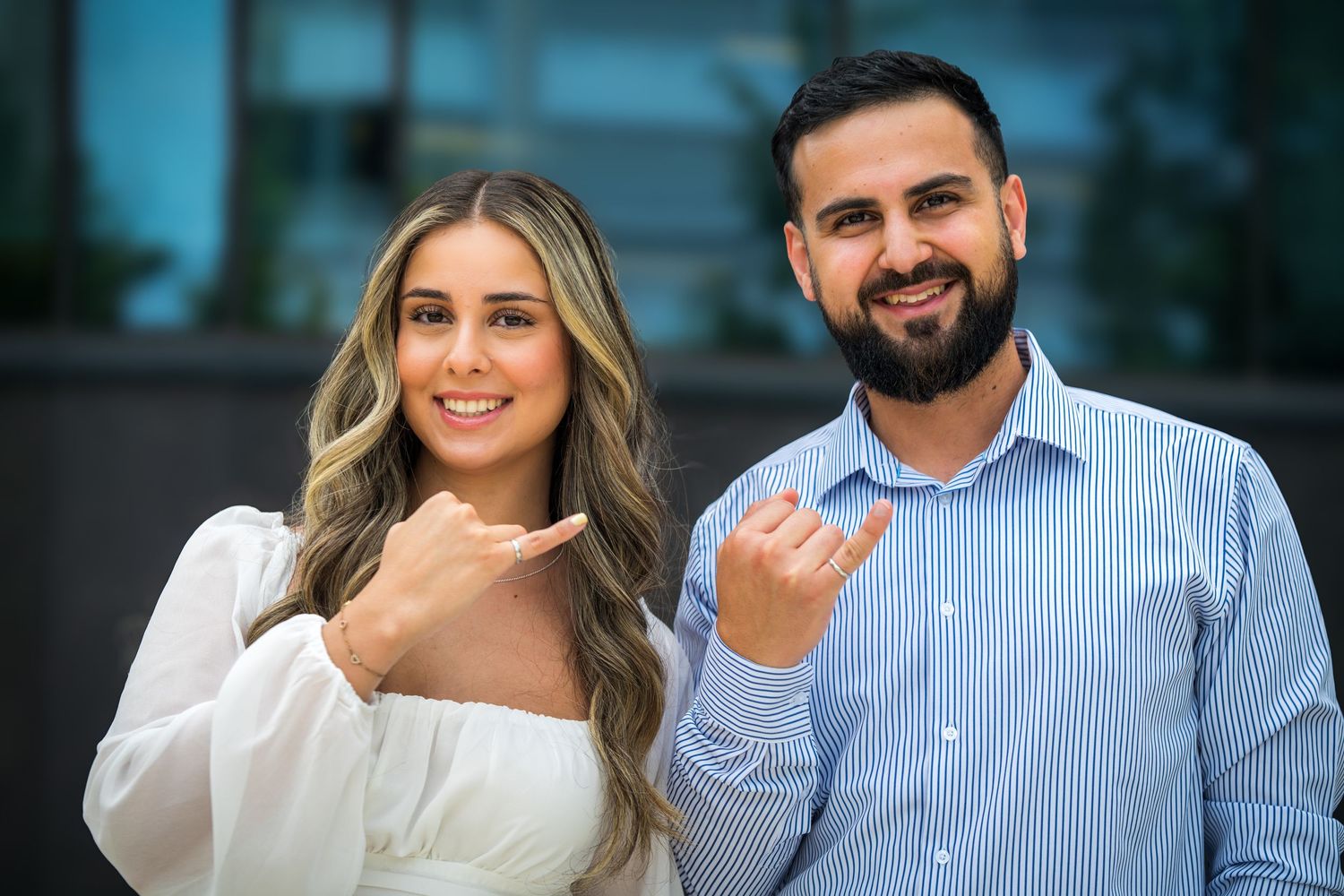 Two people share a romantic moment while dressed in white and blue business casual attire.