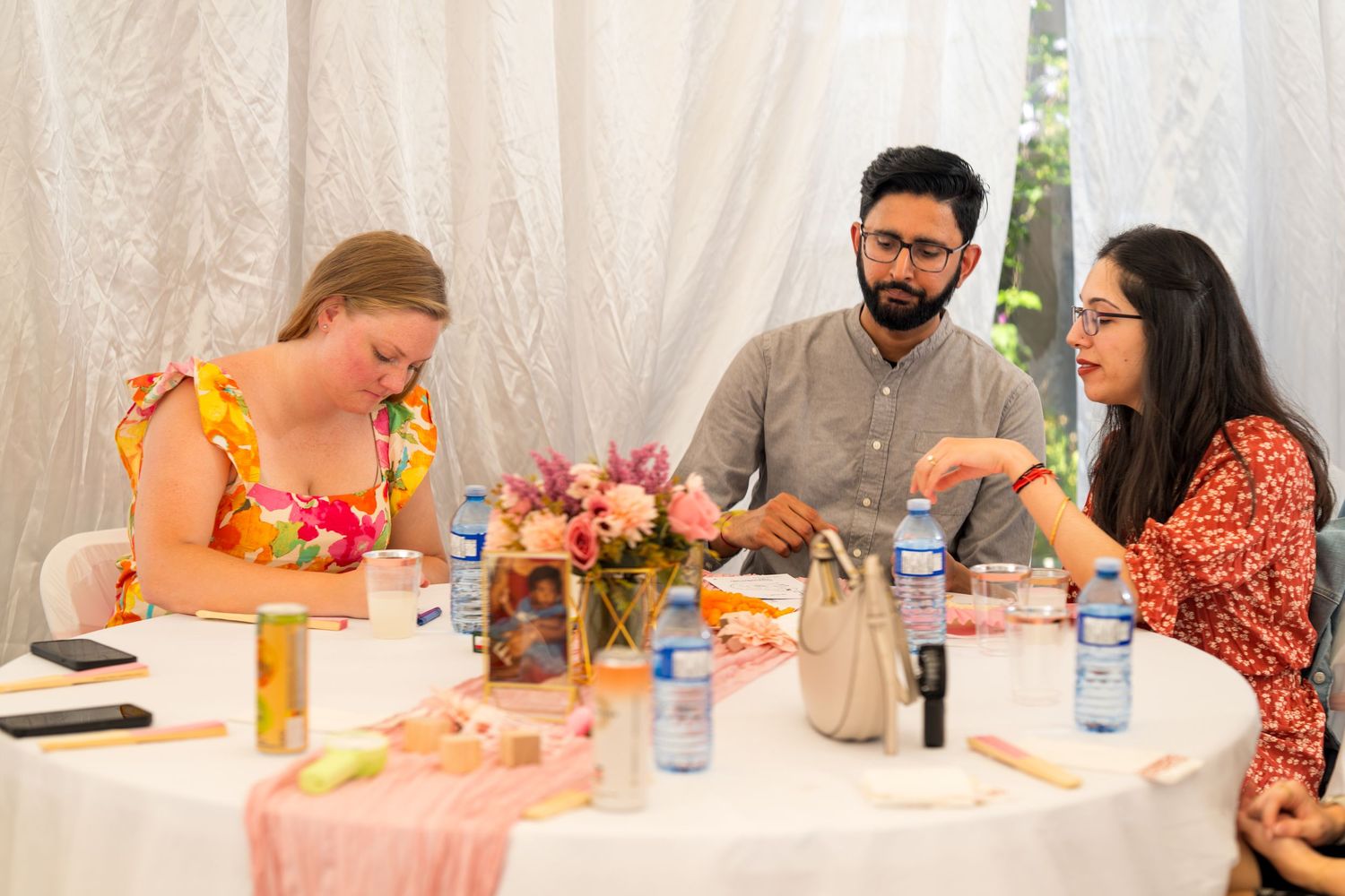 Party guests enjoying refreshments at tables decorated with pink linens.