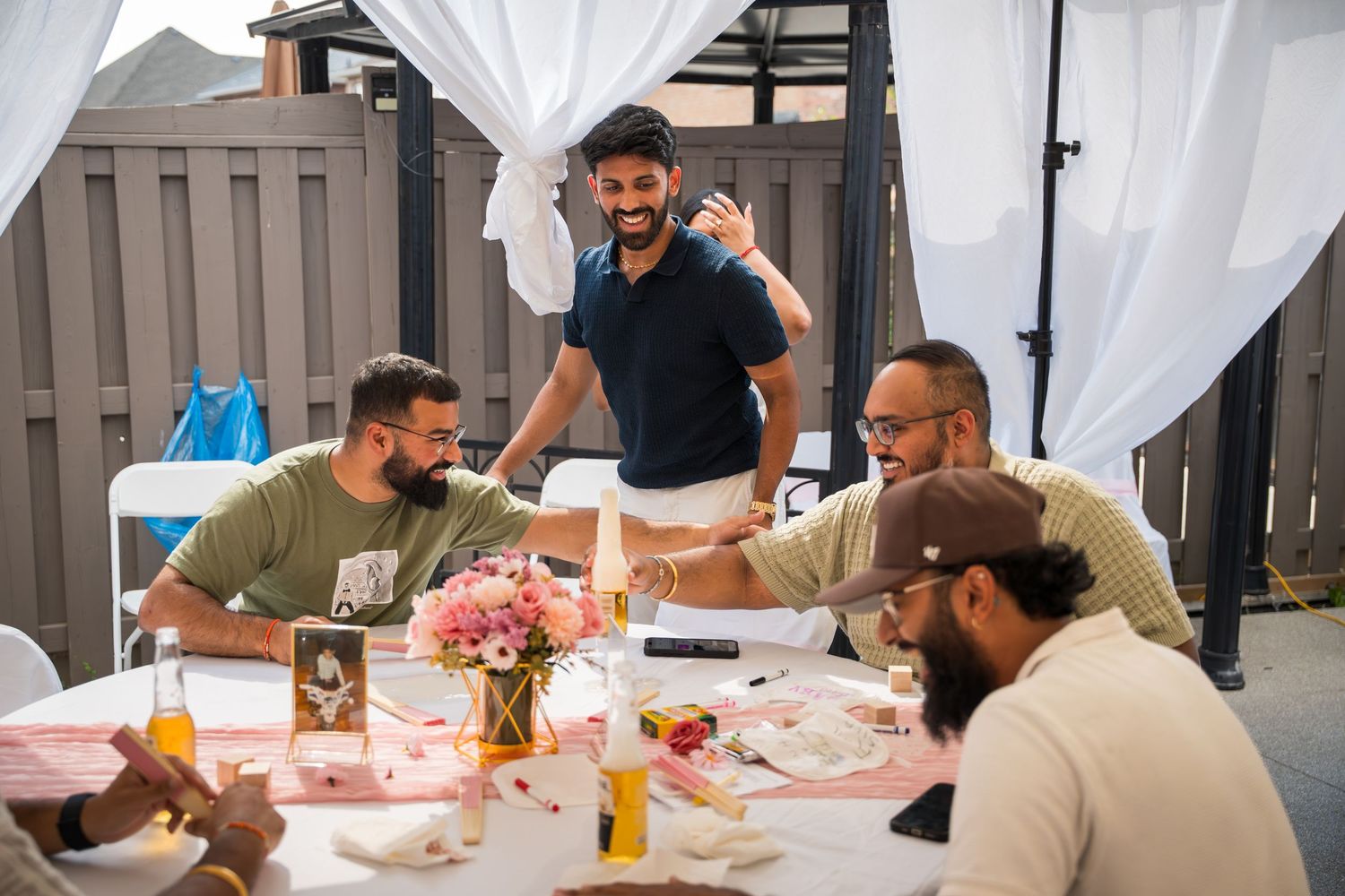 Group gathered around a table with pink decor and white curtains for a special celebration.