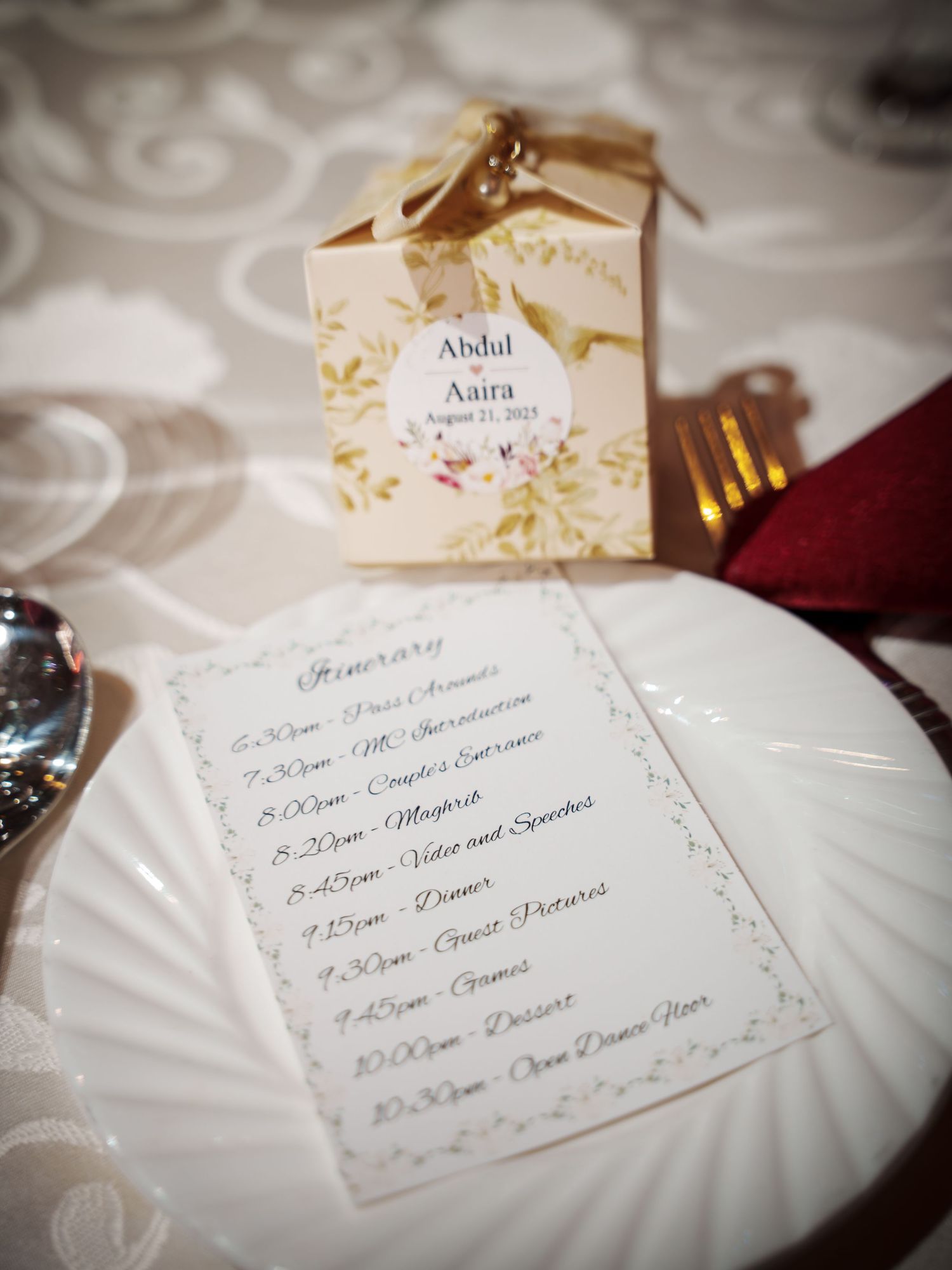 Elegant wedding menu and favor box displayed on white plate with silverware.