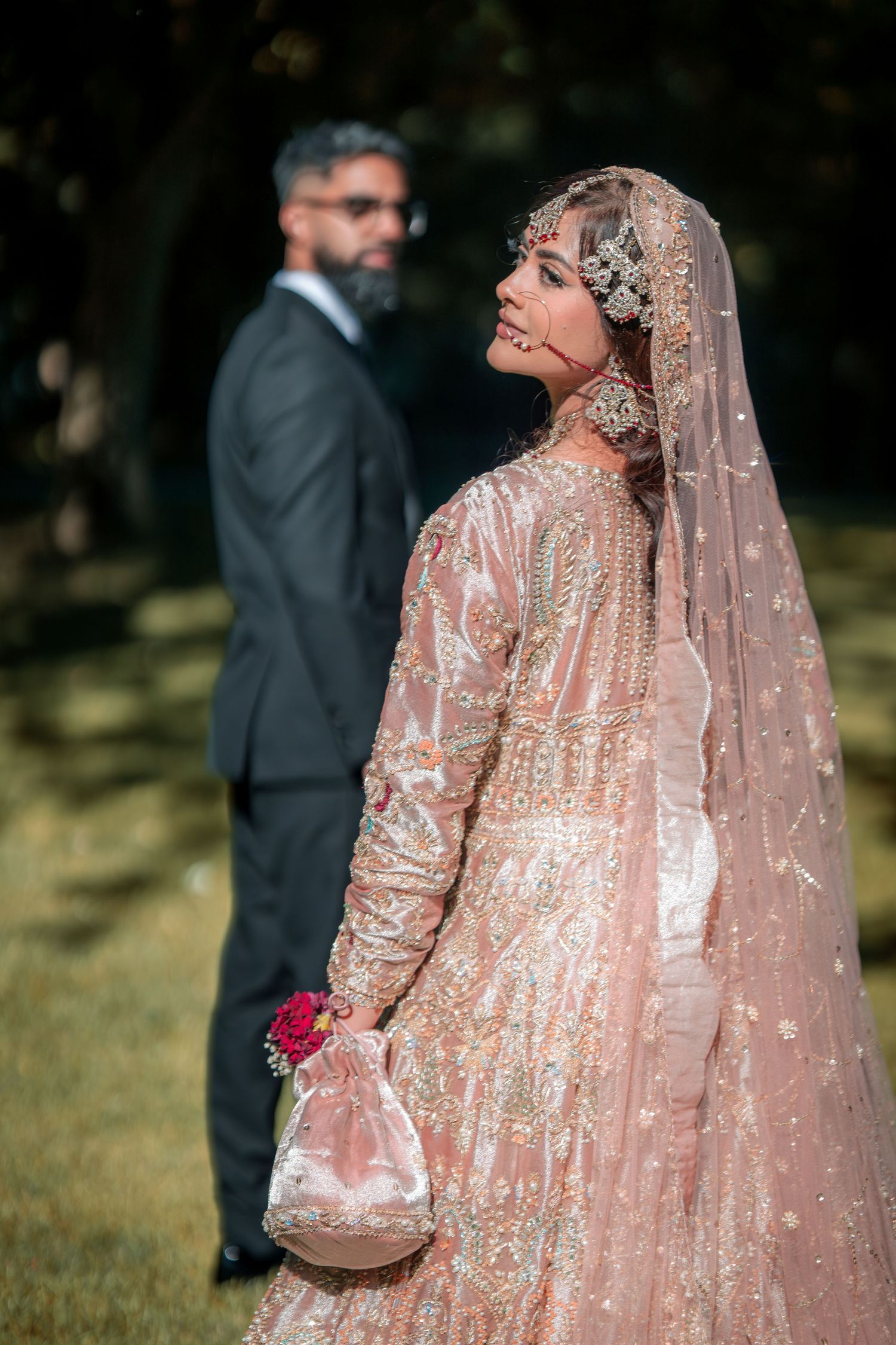 A side profile shot of a bride in an ornate peach lehenga with intricate embellishments.