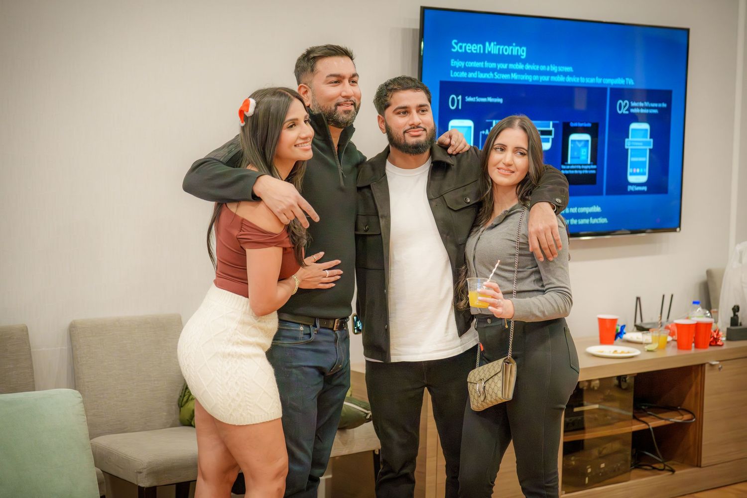 Indoor party scene with a TV mounted on the wall and people socializing.