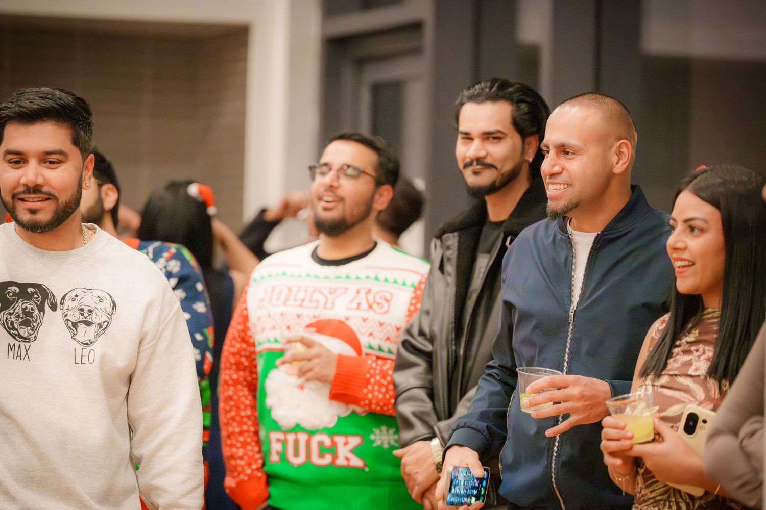 People gathered in a room wearing casual attire and holiday sweaters.