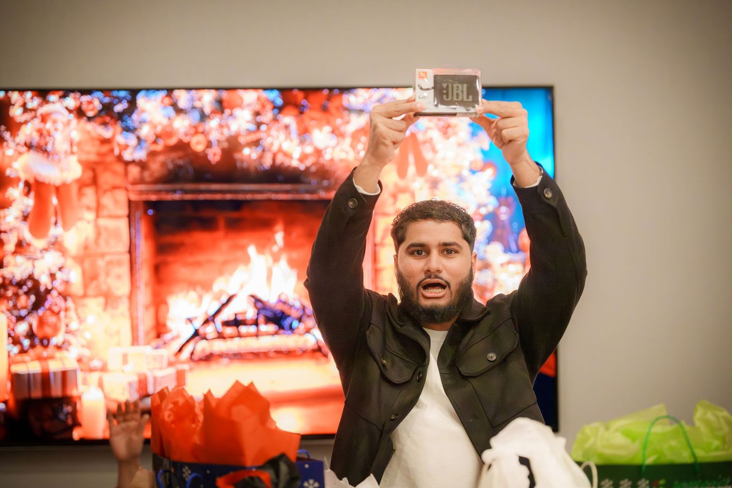 People cheering and celebrating in front of a large display screen with colorful lighting.