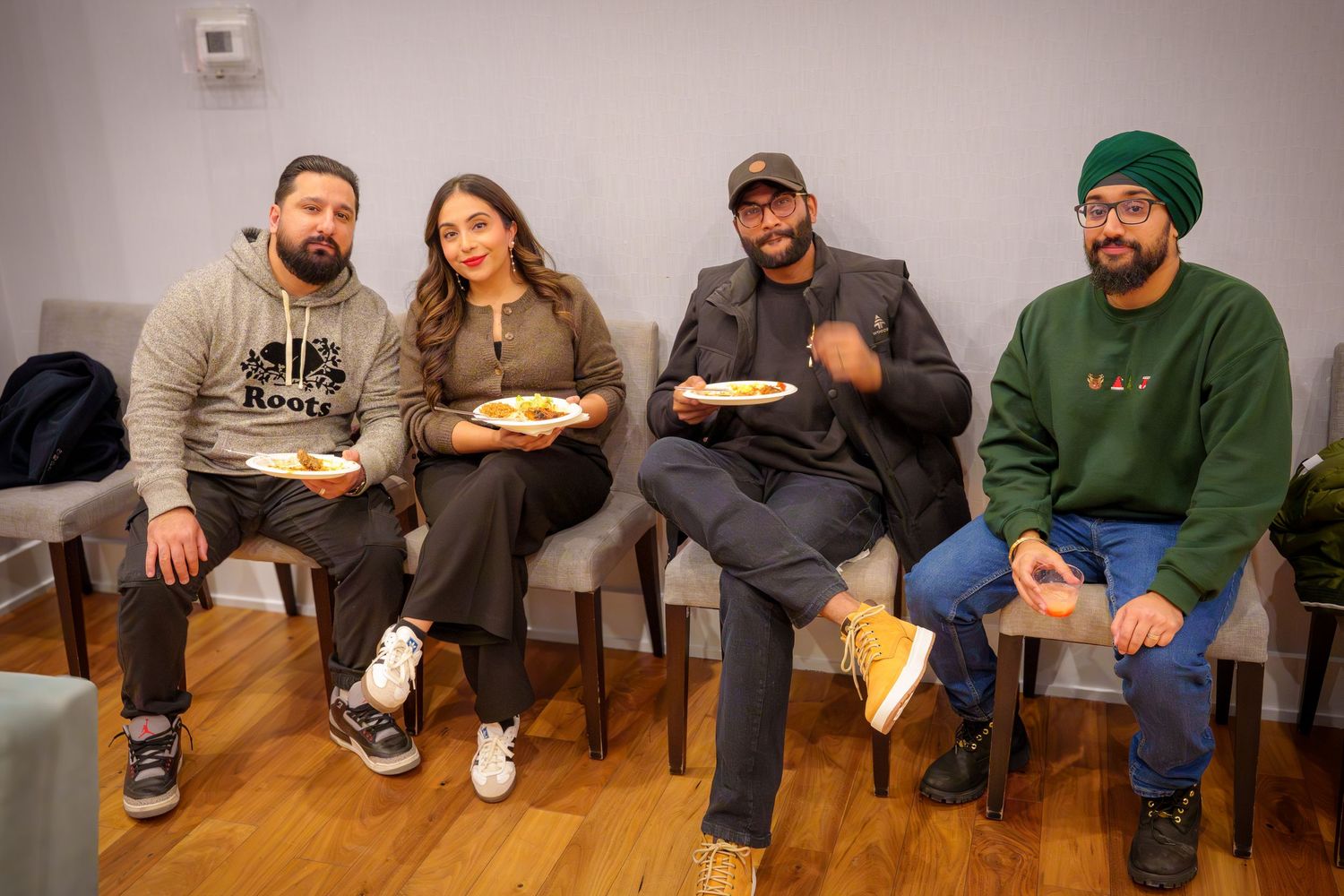Friends sit together eating snacks at a casual indoor gathering.