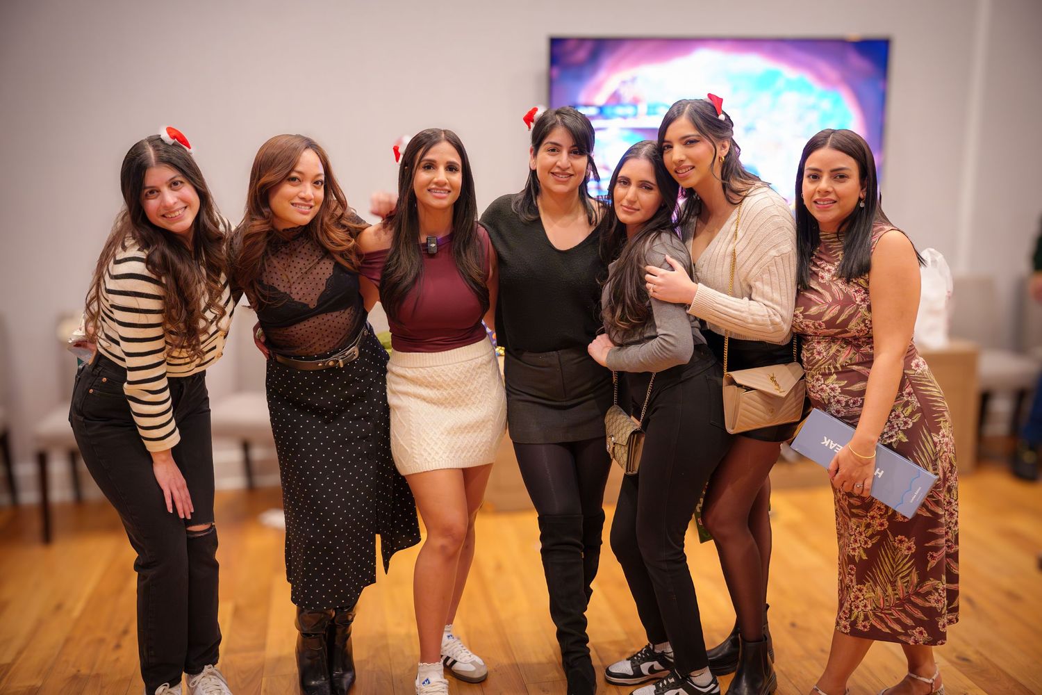 Group of friends posing together at indoor party wearing casual attire.