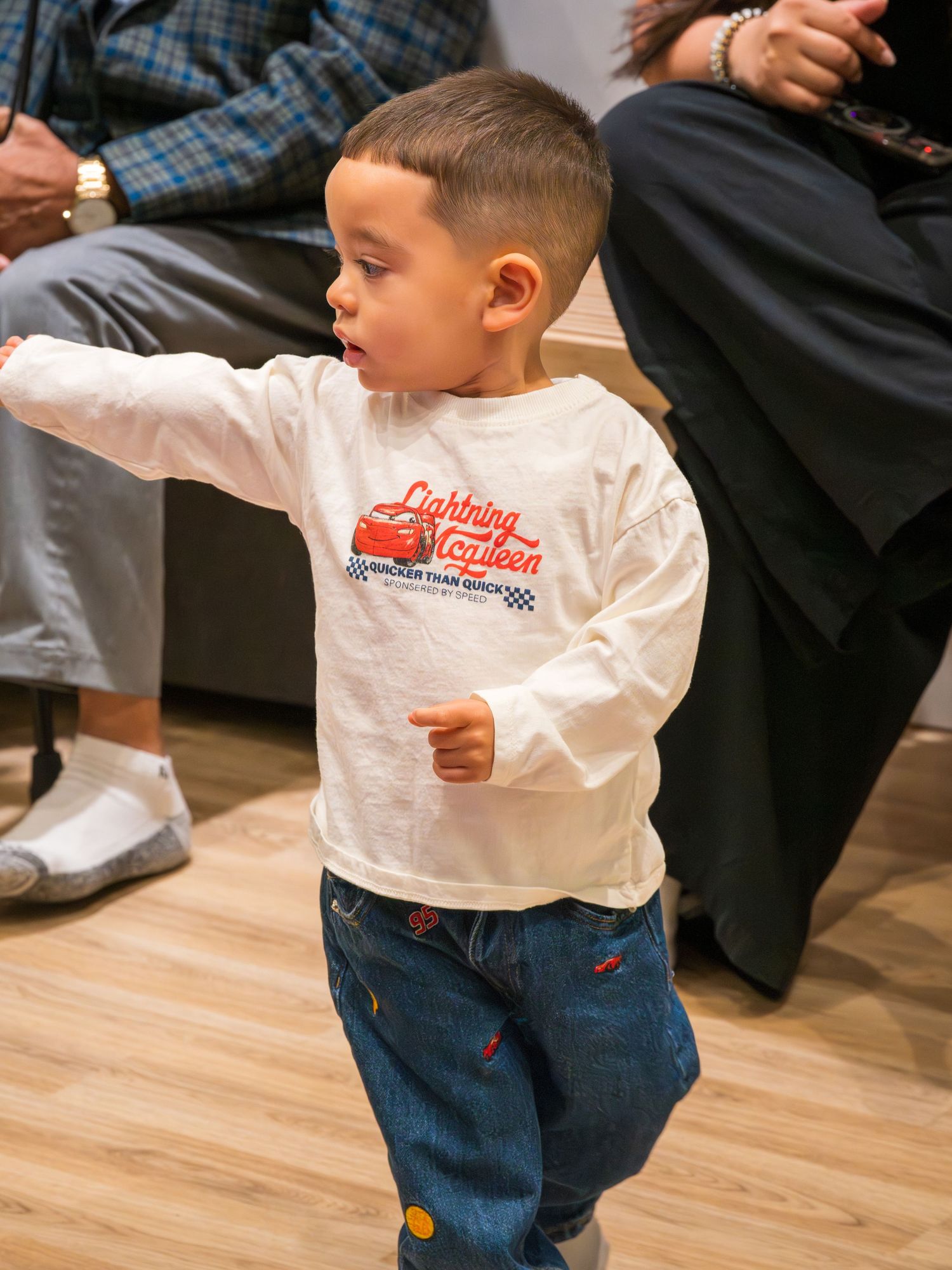 Toddler boy in Lightning McQueen shirt dancing at a birthday party event.