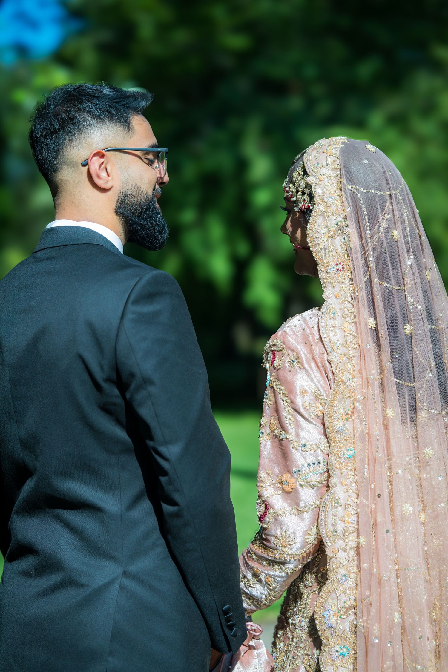 Wedding couple walking on a garden path with the bride wearing an embellished peach gown.