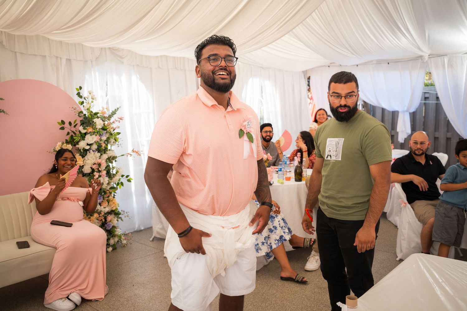 Guests mingling and socializing at an indoor event with white tent draping.
