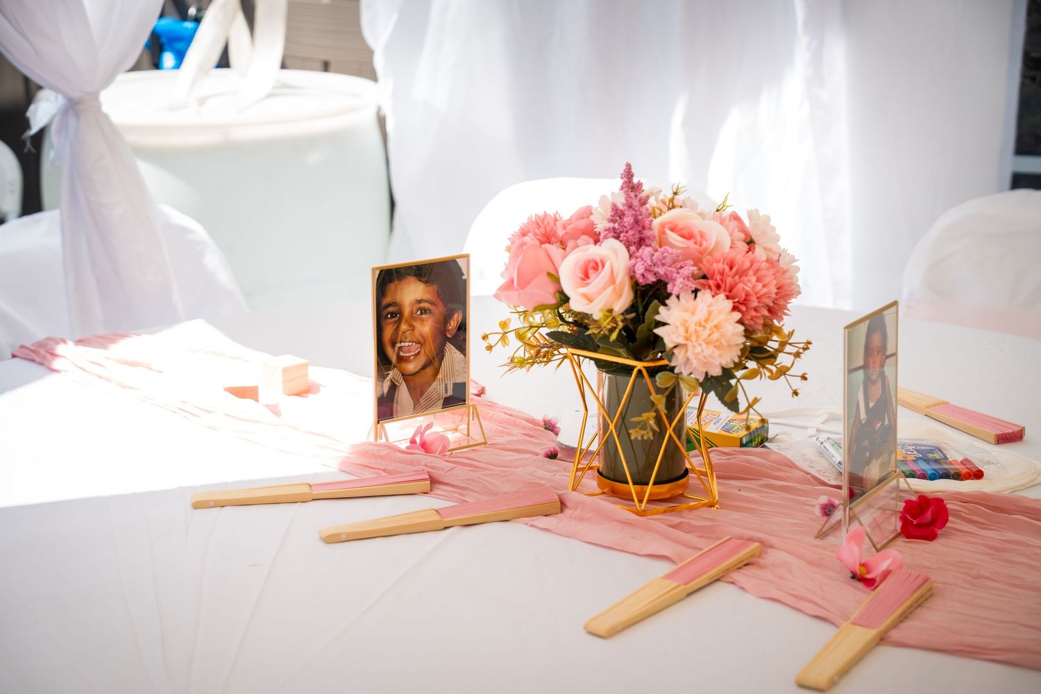 Pink themed party table with floral arrangements and decorative elements.
