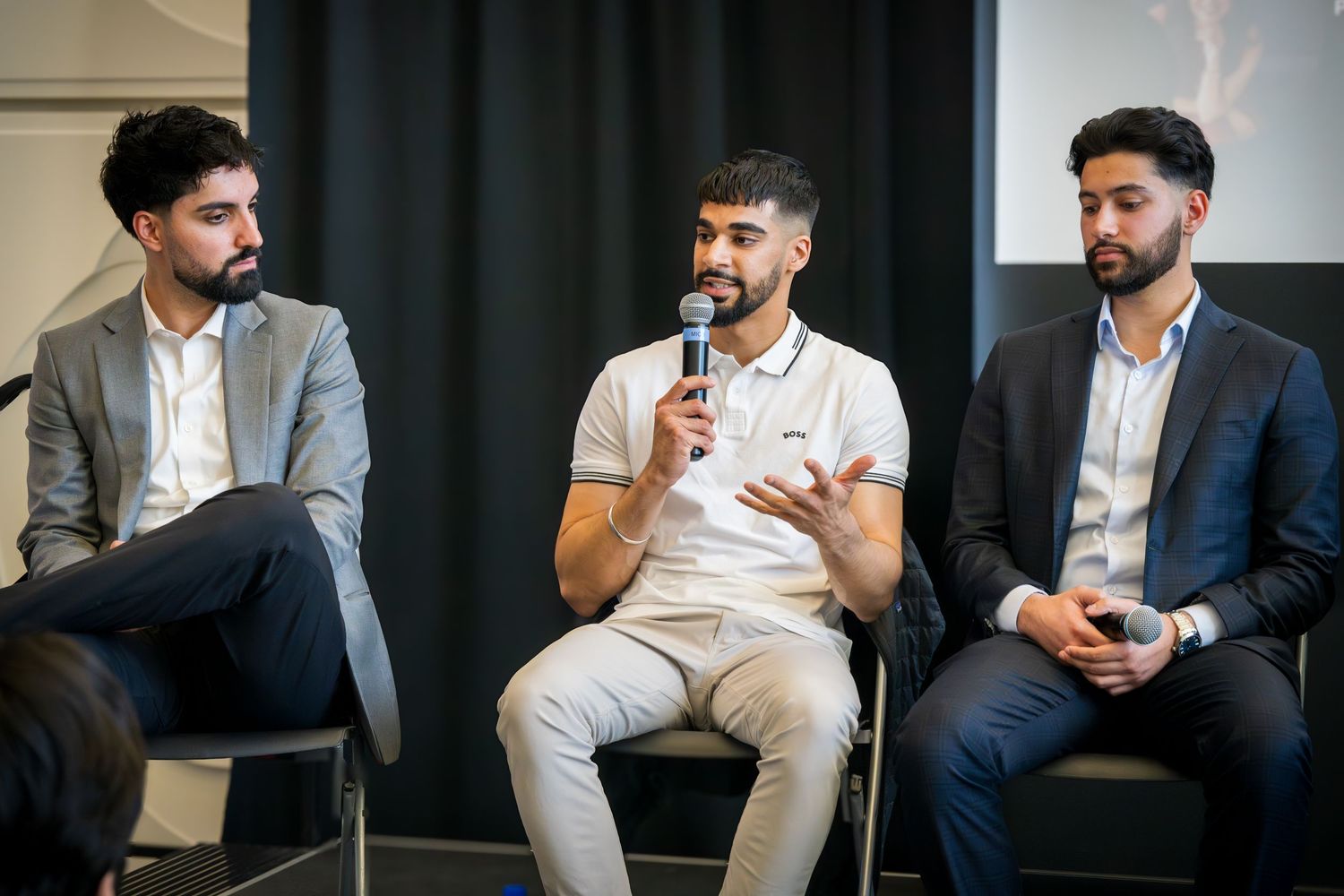 Panel speakers in business casual attire discuss topics during professional event.