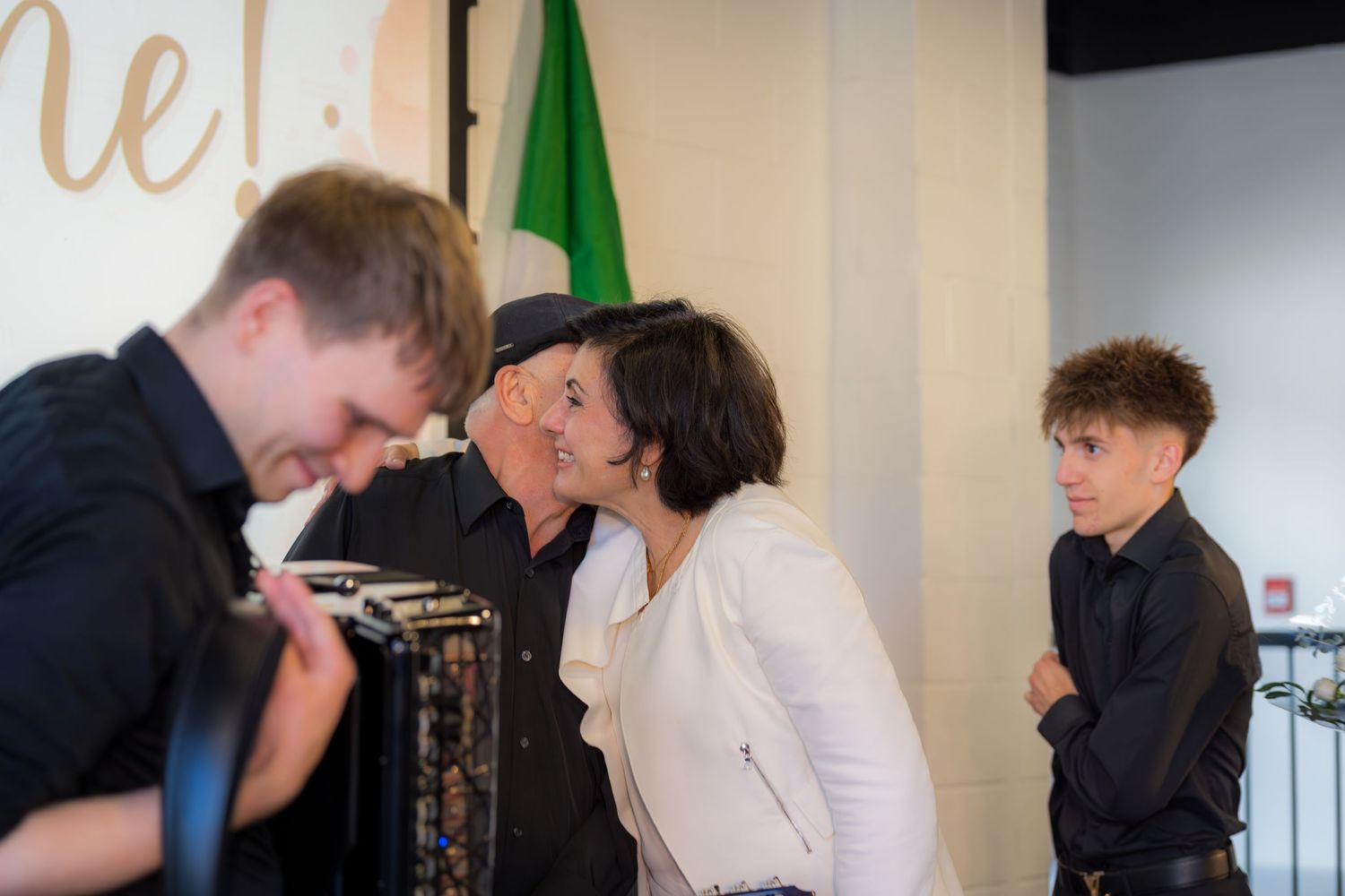 People greeting with kiss on cheek at Italian cultural music performance event.