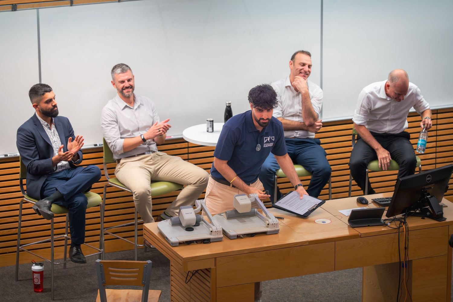 Panel discussion taking place in a lecture hall with speakers seated on wooden benches discussing topics.