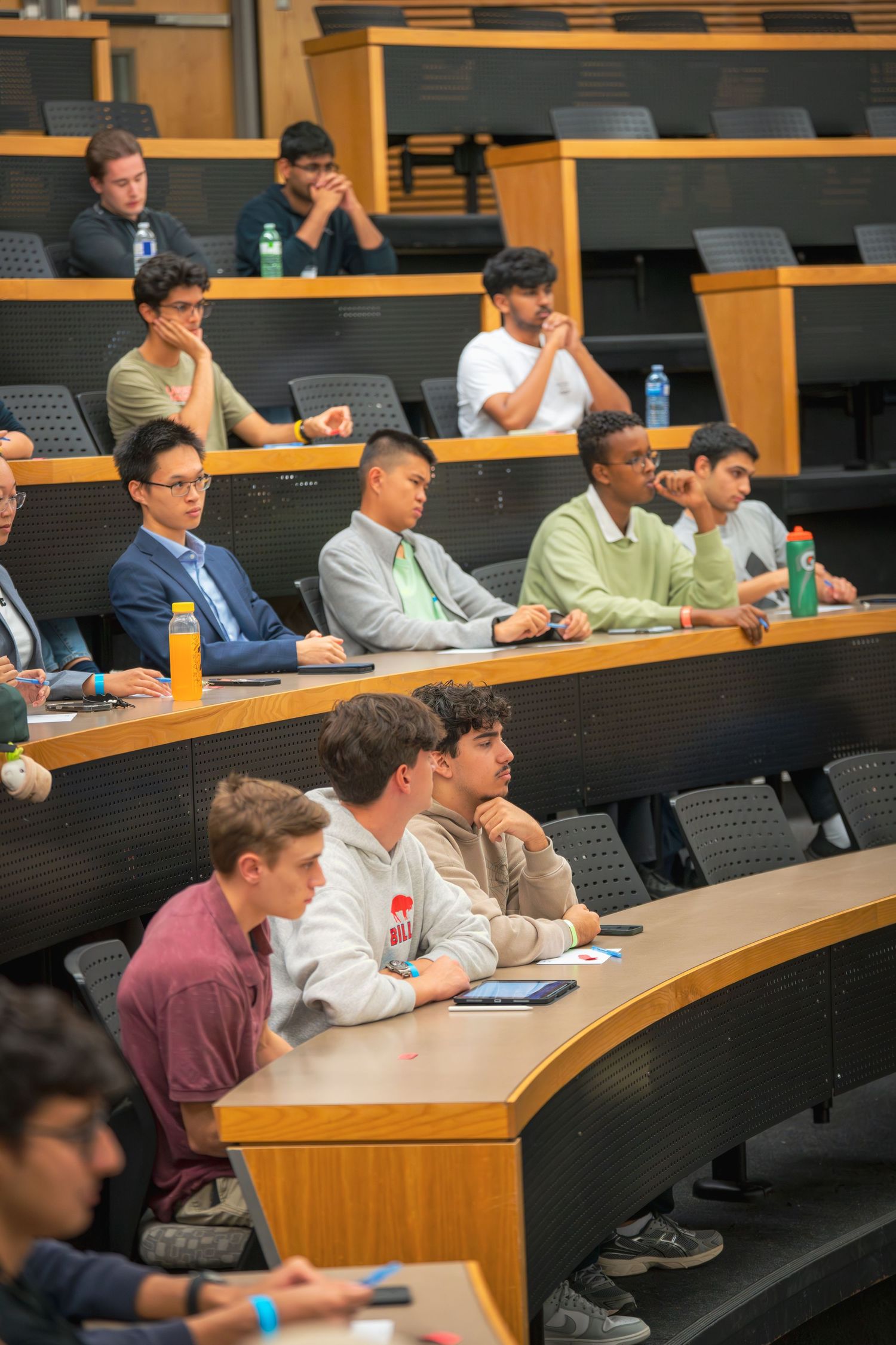 Students seated in tiered lecture hall rows during an educational presentation.