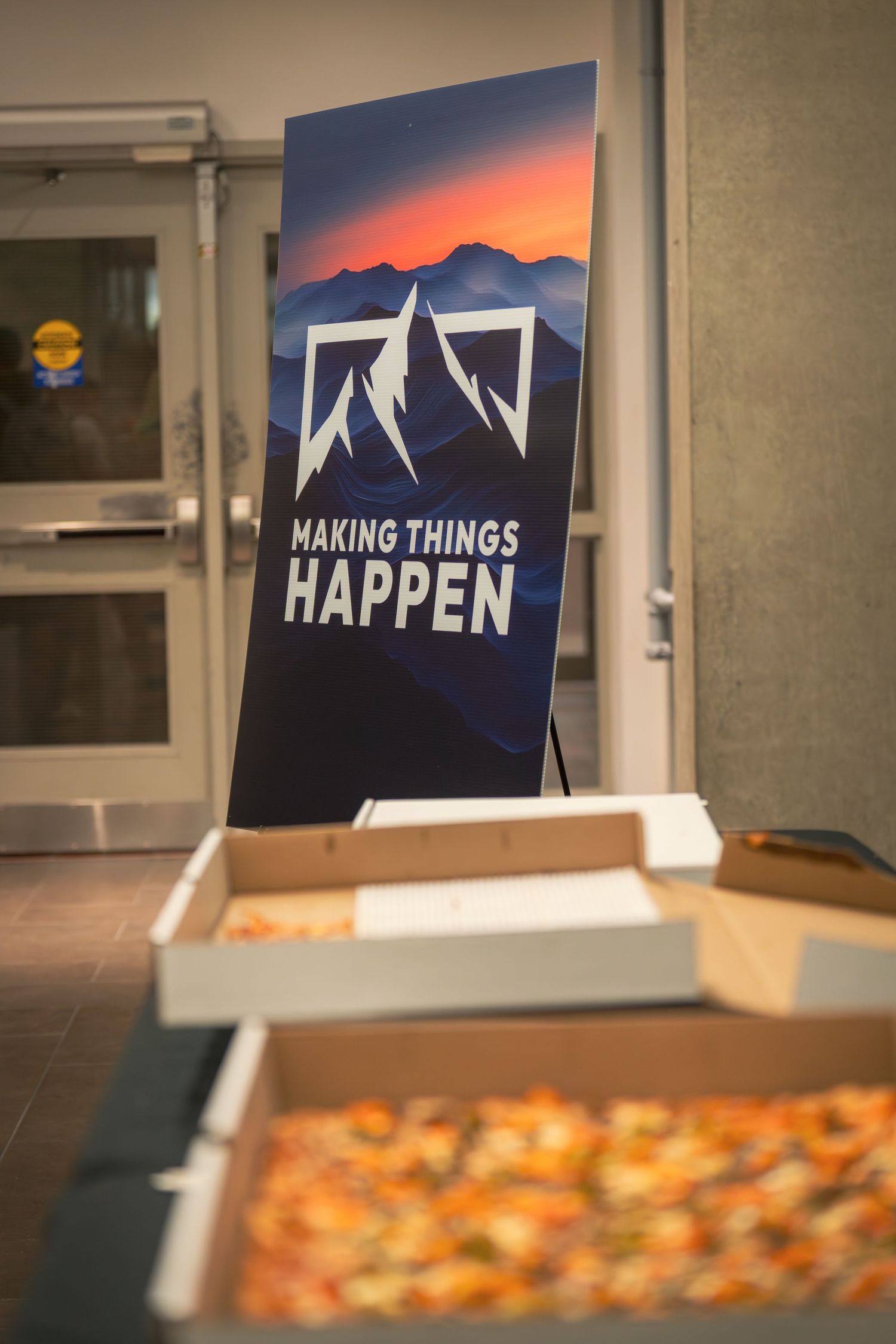 Corporate event setup with branded 'Making Things Happen' signage and refreshments.