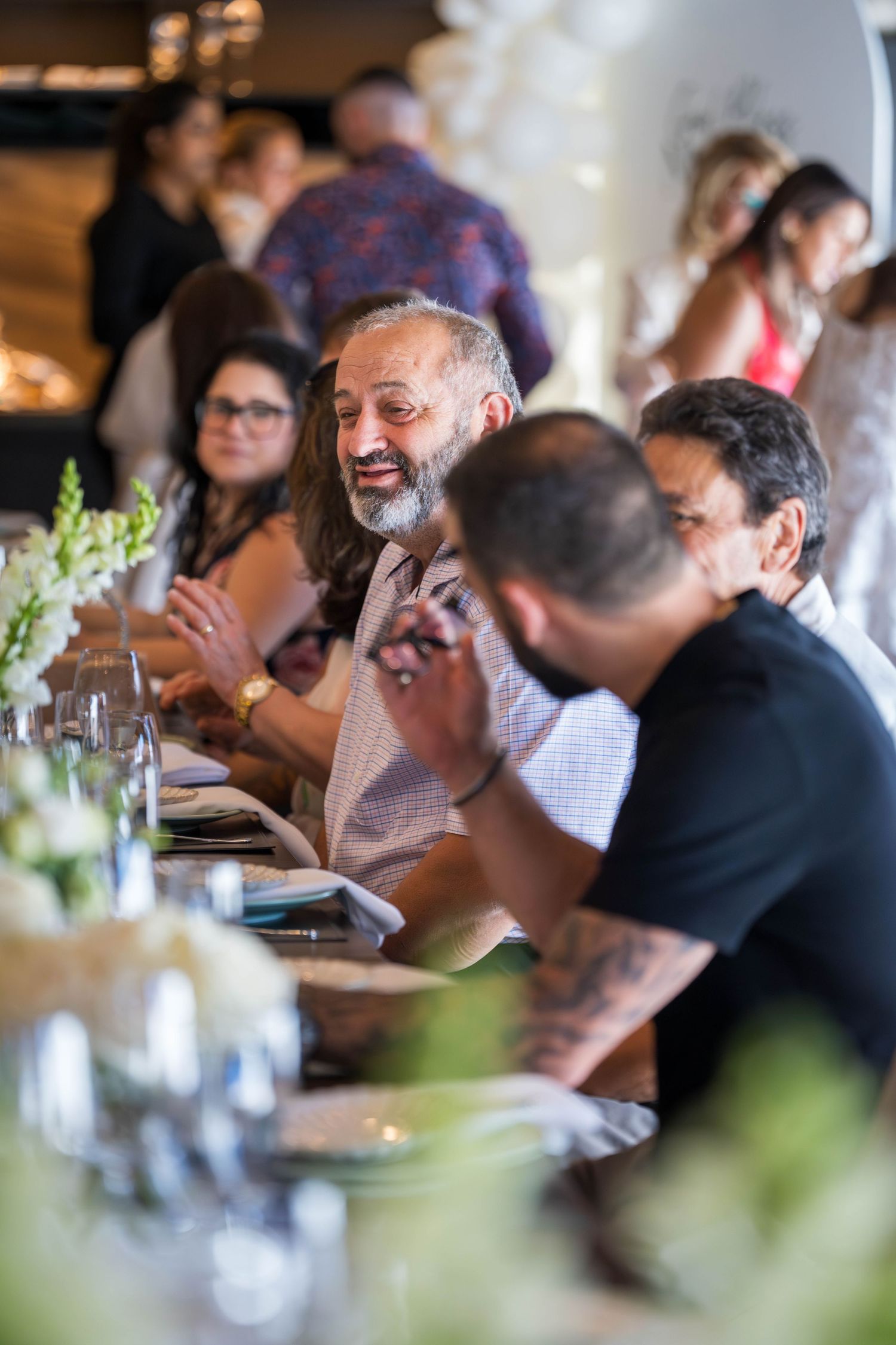 Guests seated at a dining table engage in lively conversation during a social gathering.
