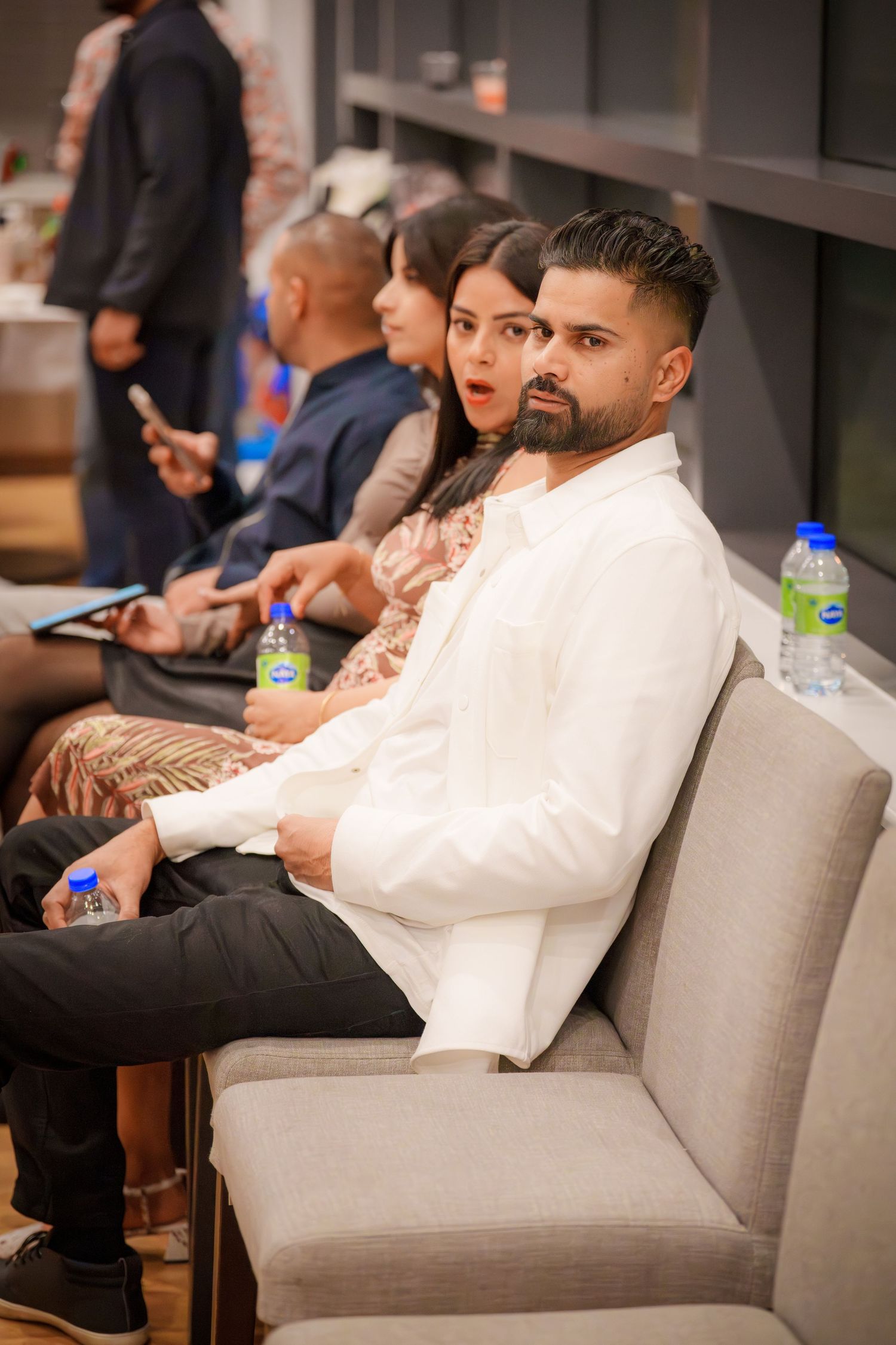 Guests relaxing on grey couches at an indoor event space.