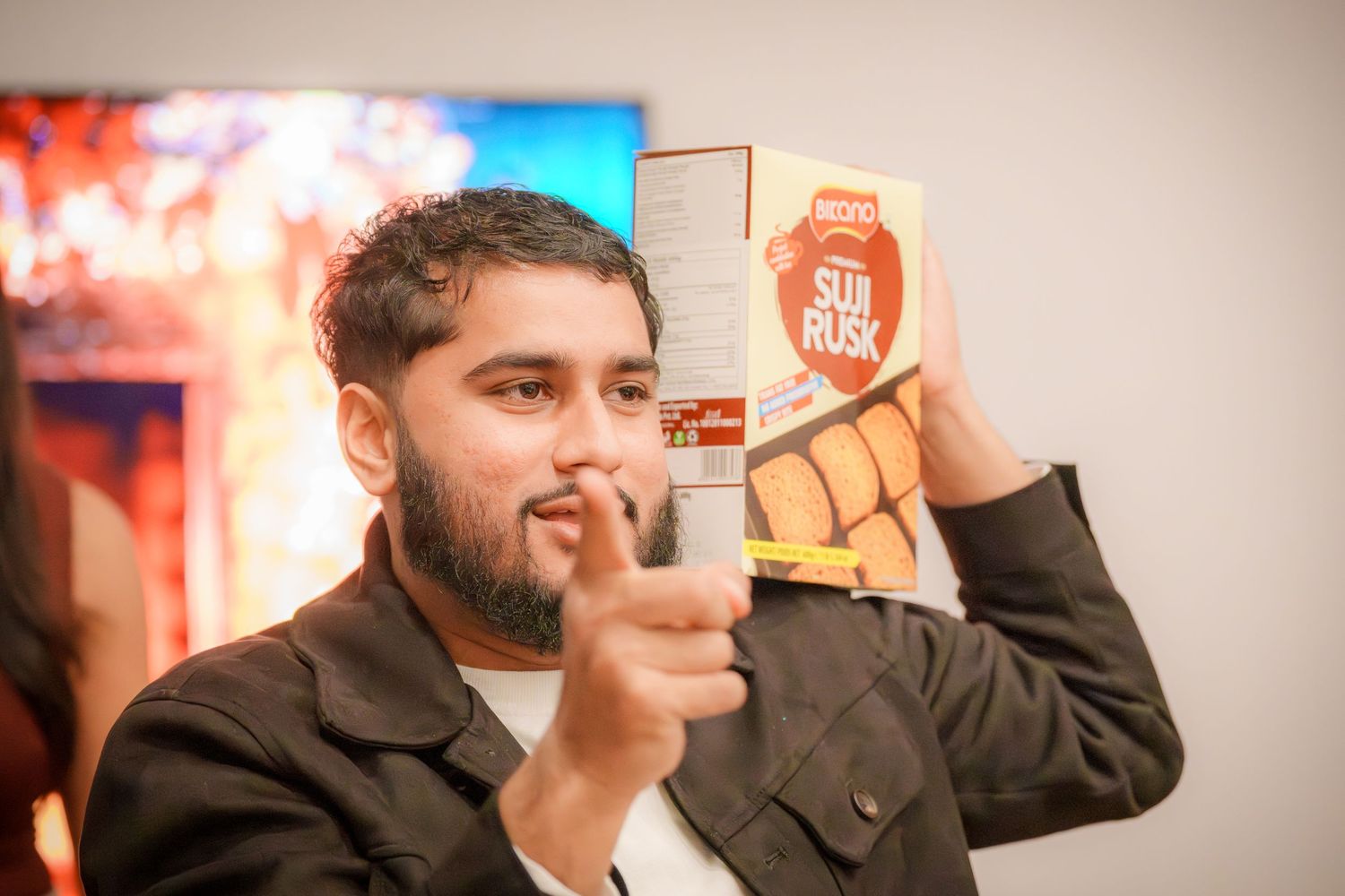 Person gesturing enthusiastically during a party with colorful lighting in background.