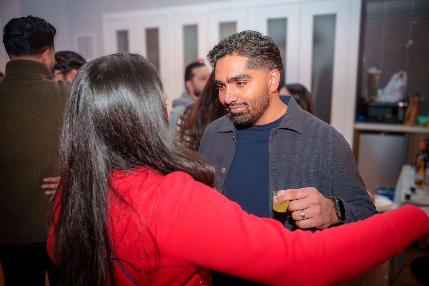 Guests share hugs and smiles during a celebratory indoor gathering.