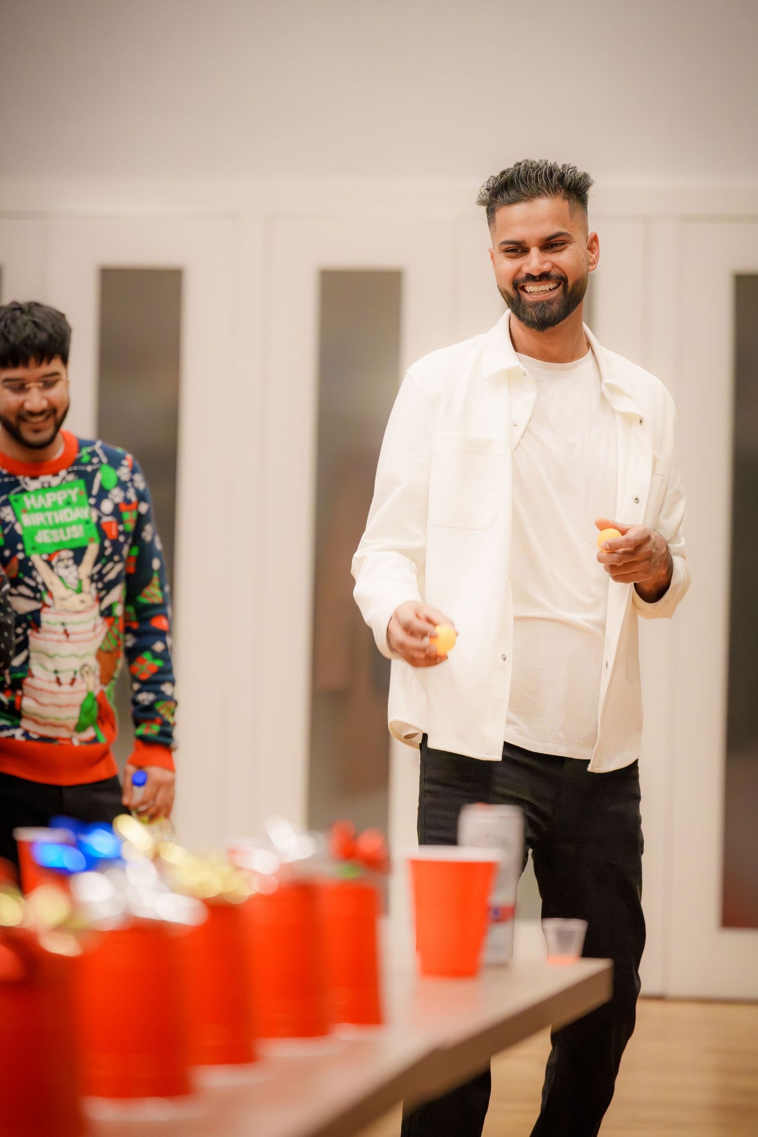 People playing a party game with red cups on a table in a modern indoor space.