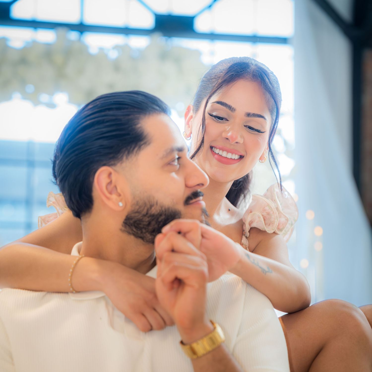 Romantic couple sharing tender moment during engagement photoshoot with bokeh lights.