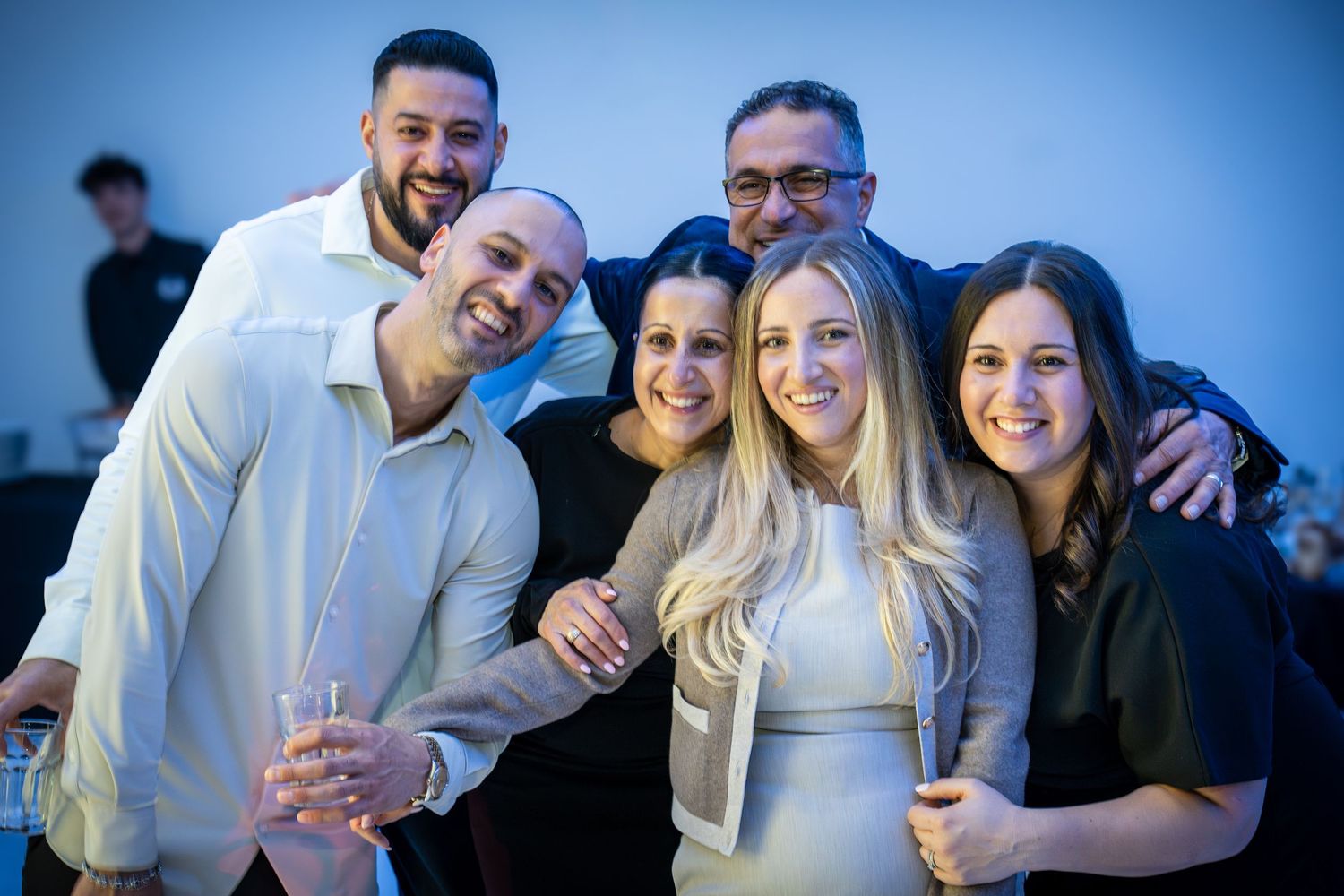 Friends gathered for group photos at an evening celebration with ambient lighting.
