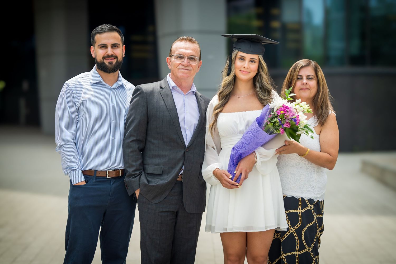 Group portrait showing formal attire and graduation cap against outdoor setting.