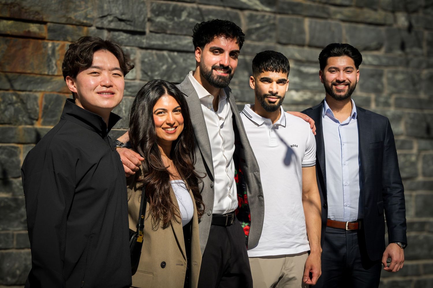 Friends gathered for a group photo against a textured brick wall.