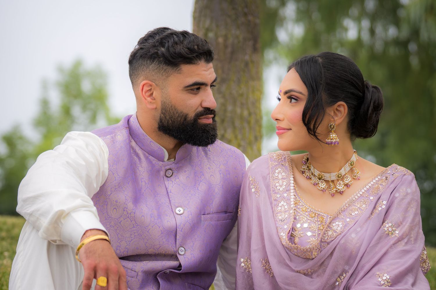Intimate outdoor photoshoot featuring couple in traditional South Asian inspired formal wear.