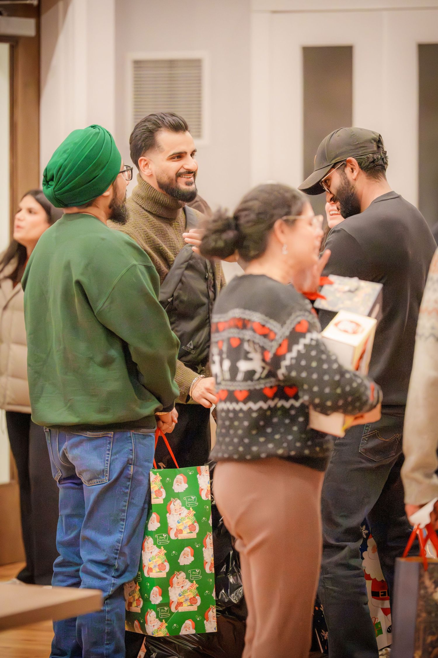 A group of people socializing at an indoor gathering with holiday gift bags.