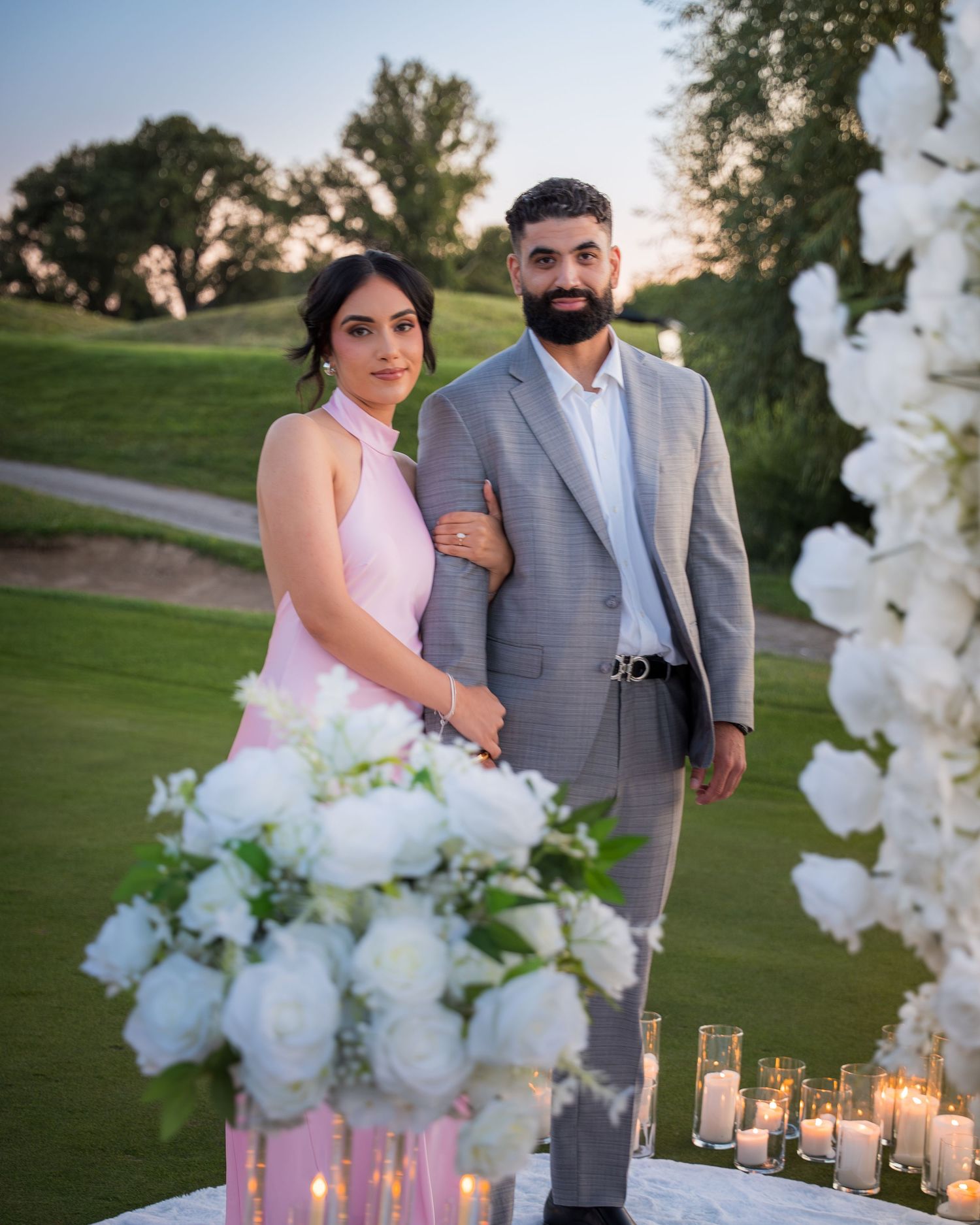 Engagement photos on golf course with elegant floral and candle decorations.