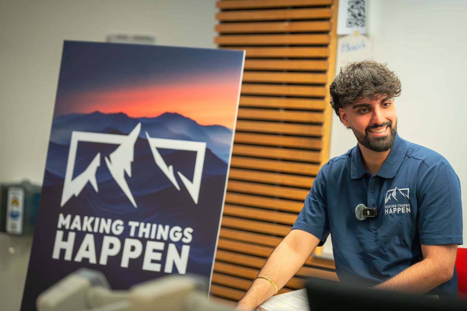 Speaker poses next to 'Making Things Happen' banner featuring mountain silhouettes at sunset.
