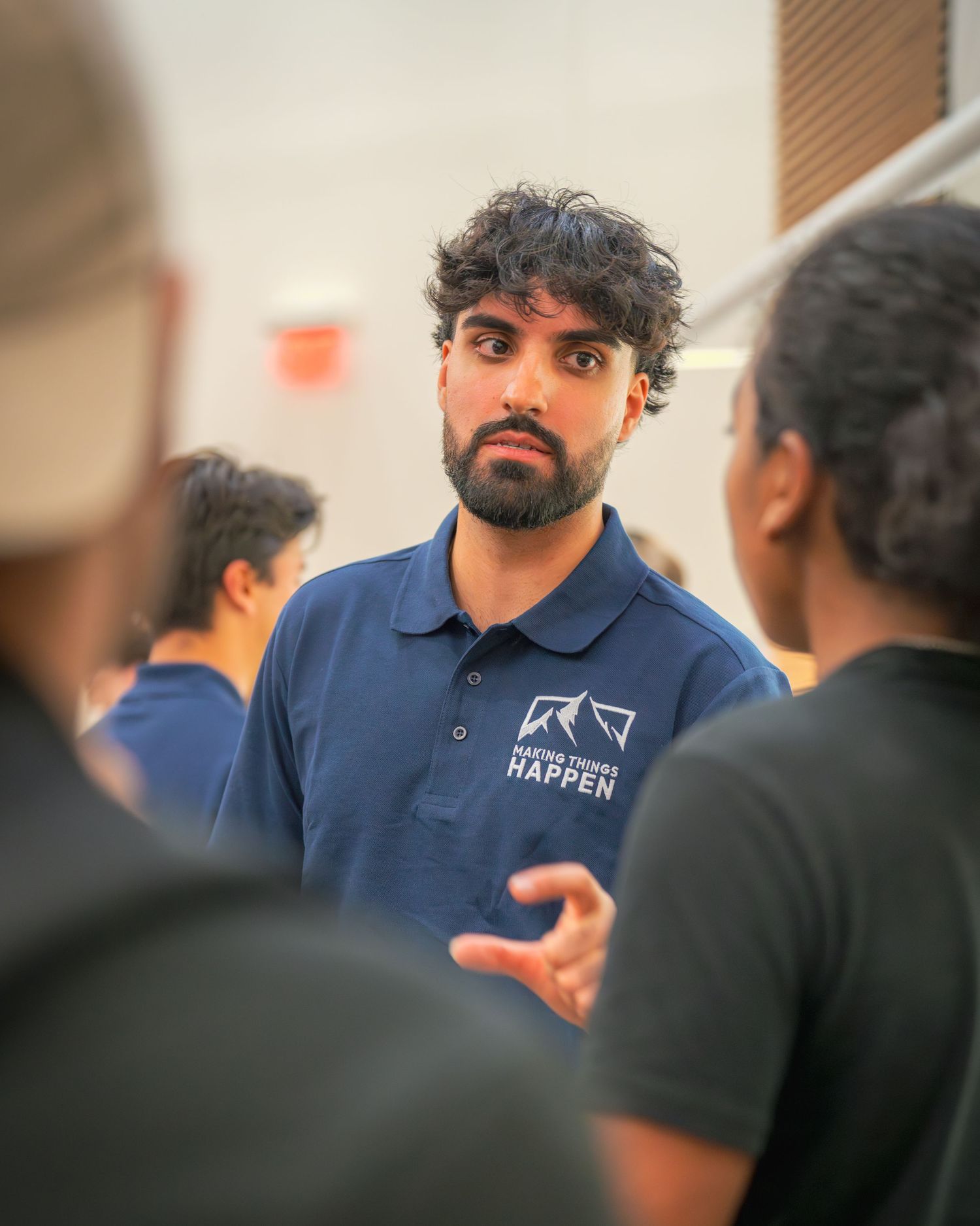 A presenter in a navy polo shirt engages with audience members during a discussion.