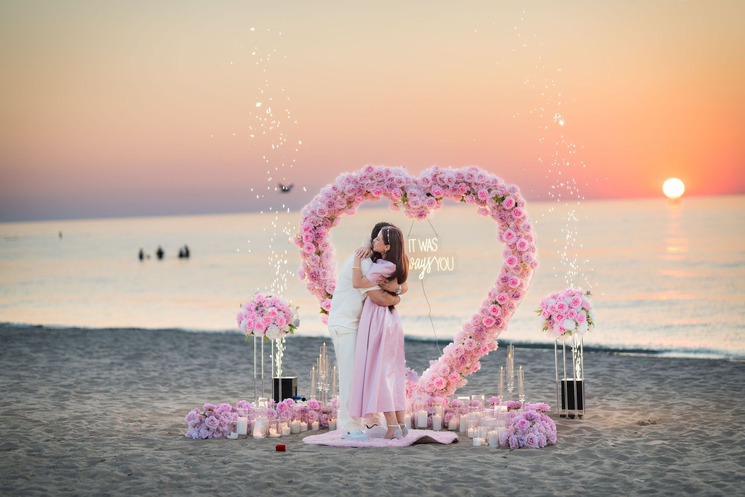 Pink floral arch decorations on beach at sunset create romantic atmosphere for intimate seaside ceremony.