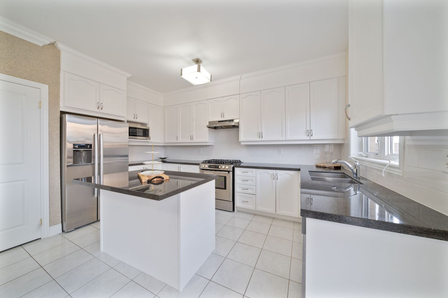 Spacious all-white kitchen featuring tiled floors, ample cabinet storage, and recessed lighting in an open floor plan.