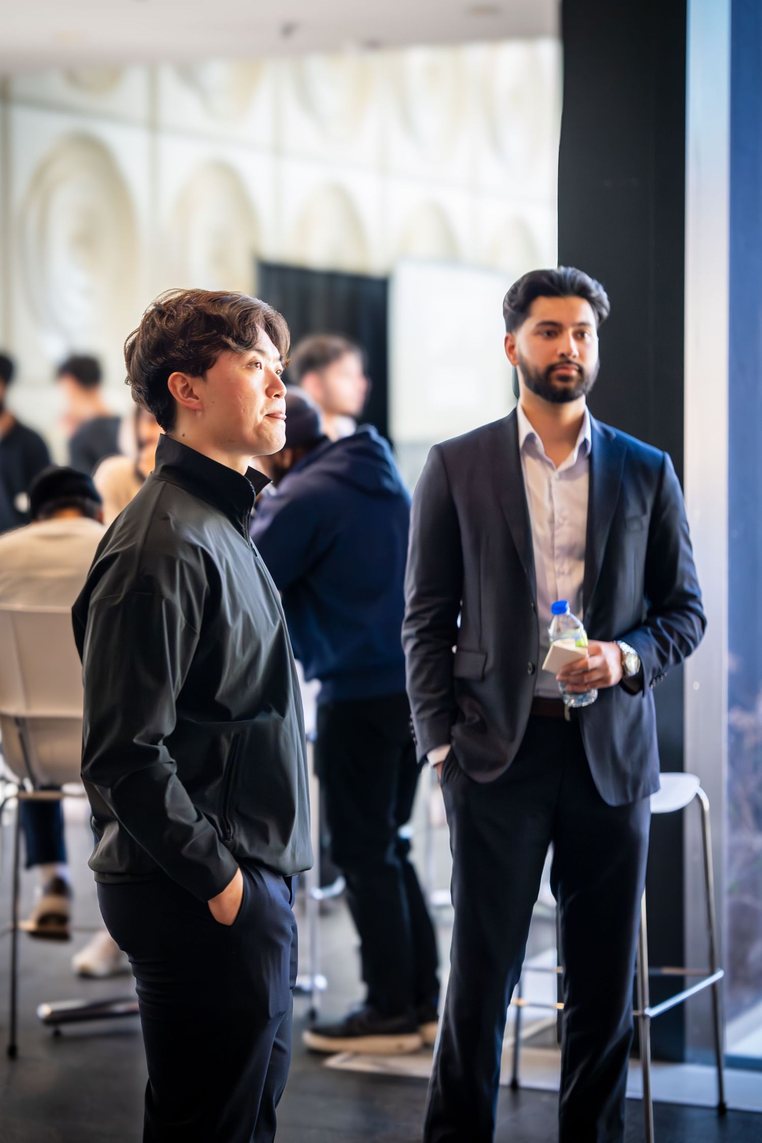Business professionals networking and mingling in a modern office hallway with blue lighting.