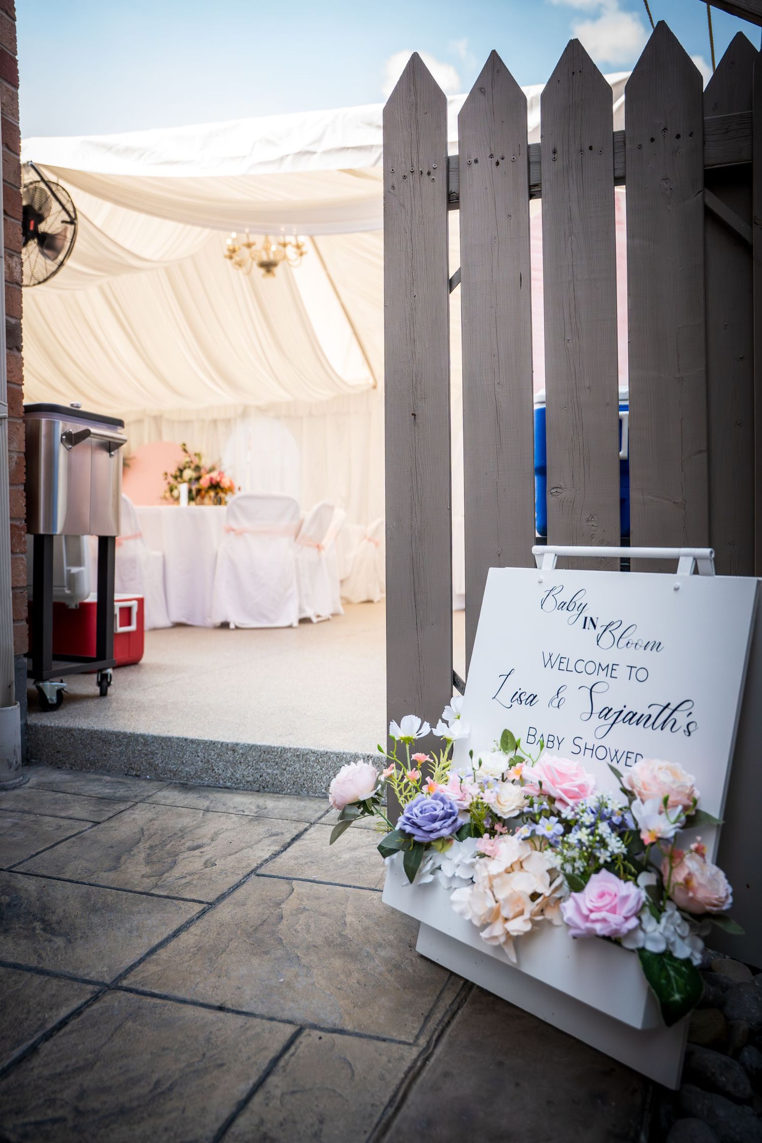 White picket fence entrance with welcome signs and floral decorations.