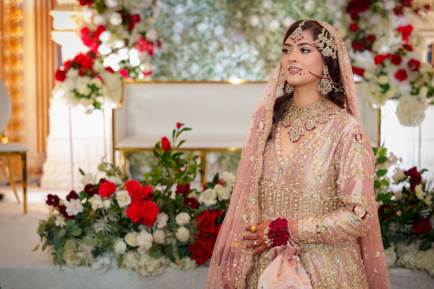 Wedding ceremony setup with red and white floral arrangements against elegant backdrop.