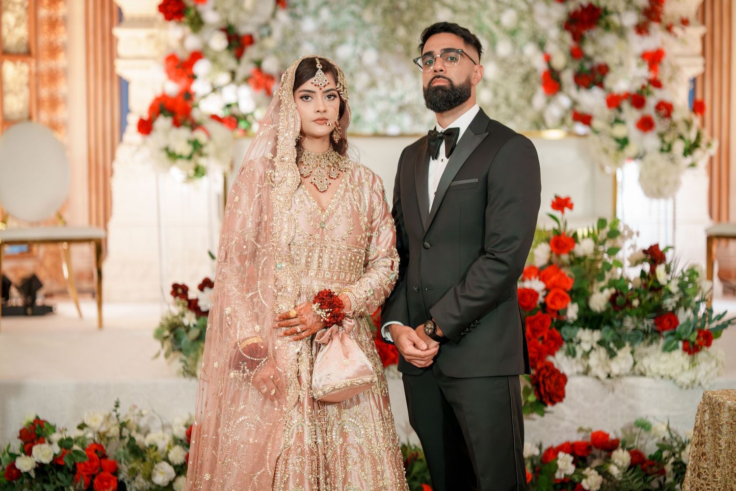 Wedding ceremony setup with red and white floral arch and elegant decor.