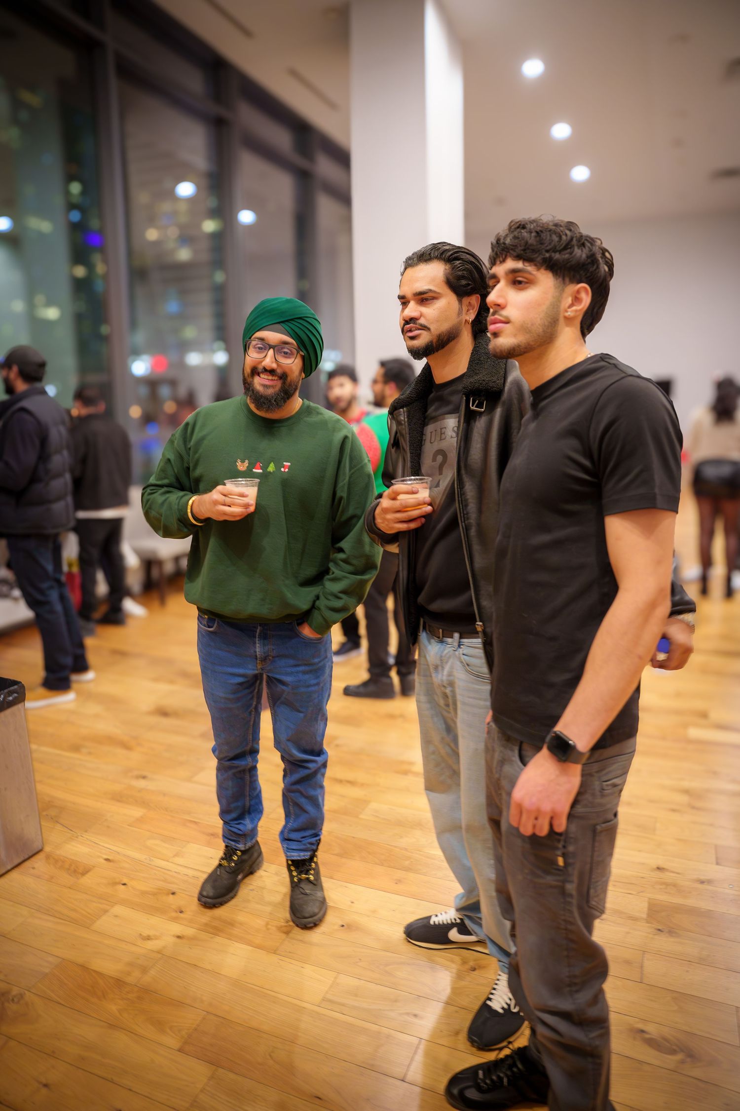 People gathered at an indoor event with hardwood flooring and white walls.