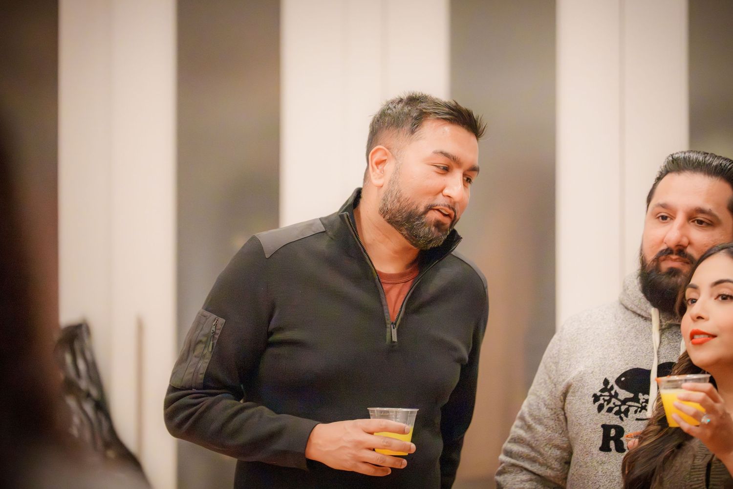 Friends enjoying drinks and conversation at an indoor social event.