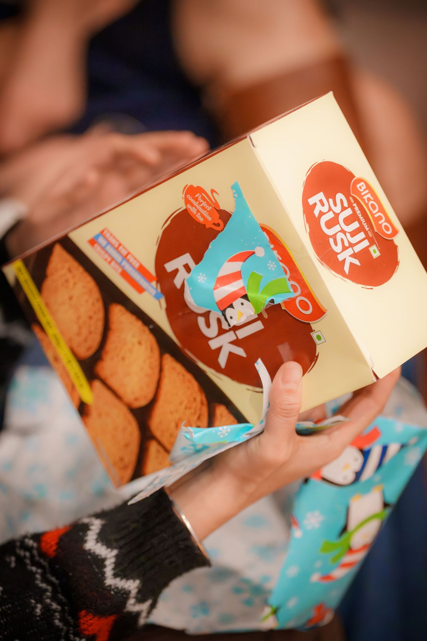 A hand holding a box of Girl Scout cookies at a social event.