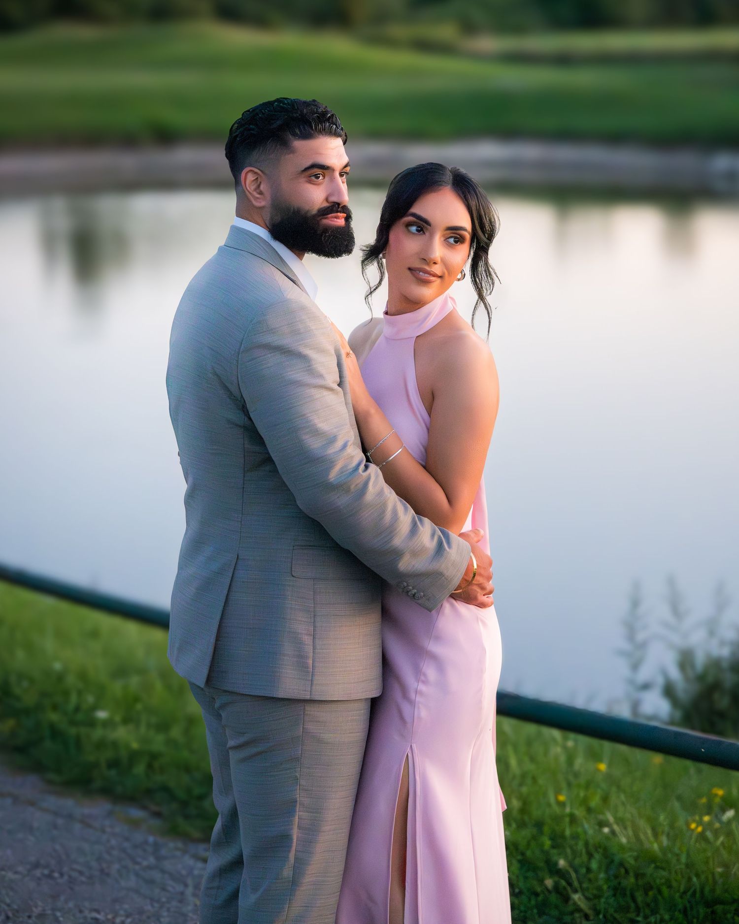 Romantic lakeside portraits of couple in pink dress and grey suit during sunset.