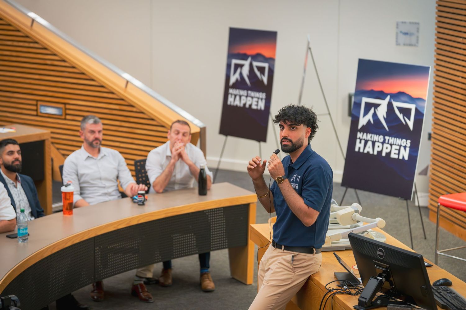 Group discussion in a meeting room with branded banners visible on the wall.