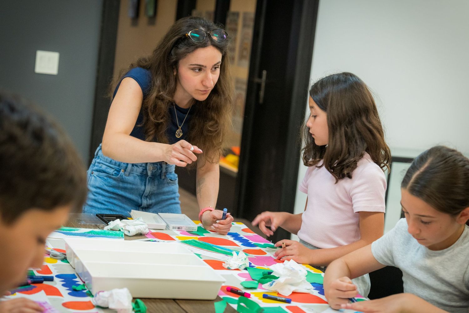 Art instructor engages with children during colorful paper craft activity at creative kids workshop.