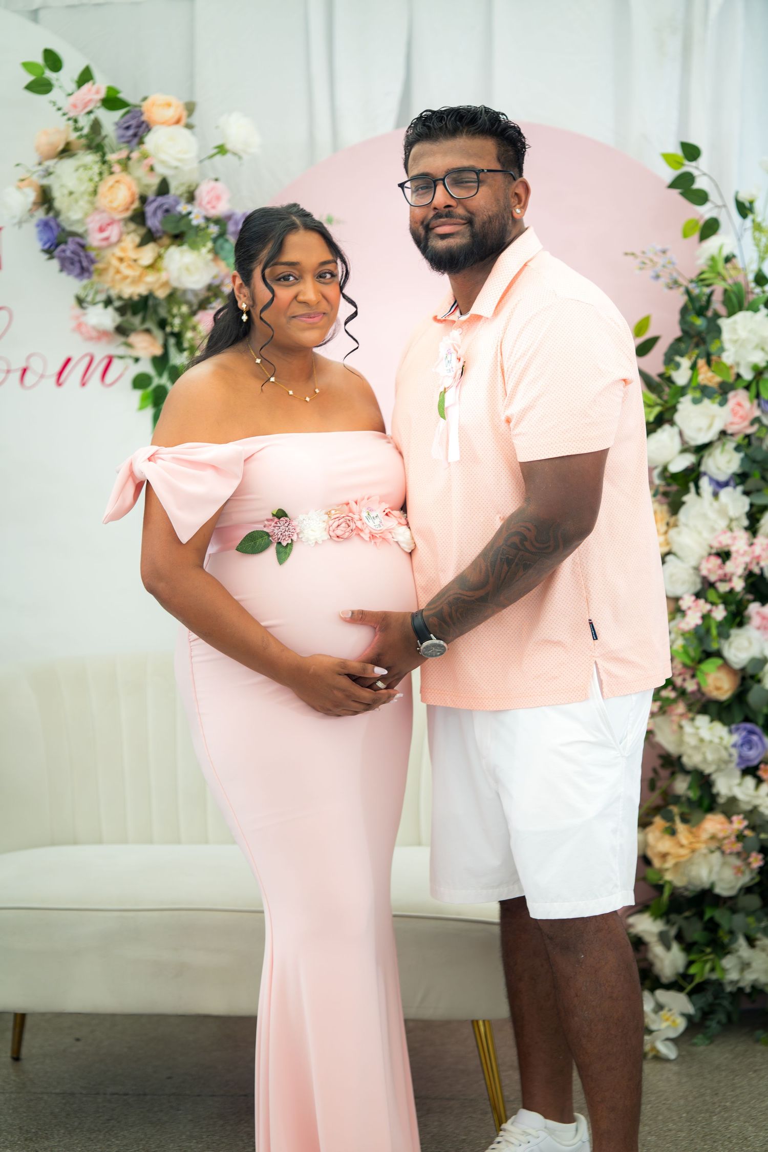 A couple shares an intimate moment in front of a decorative floral wall at a special event.