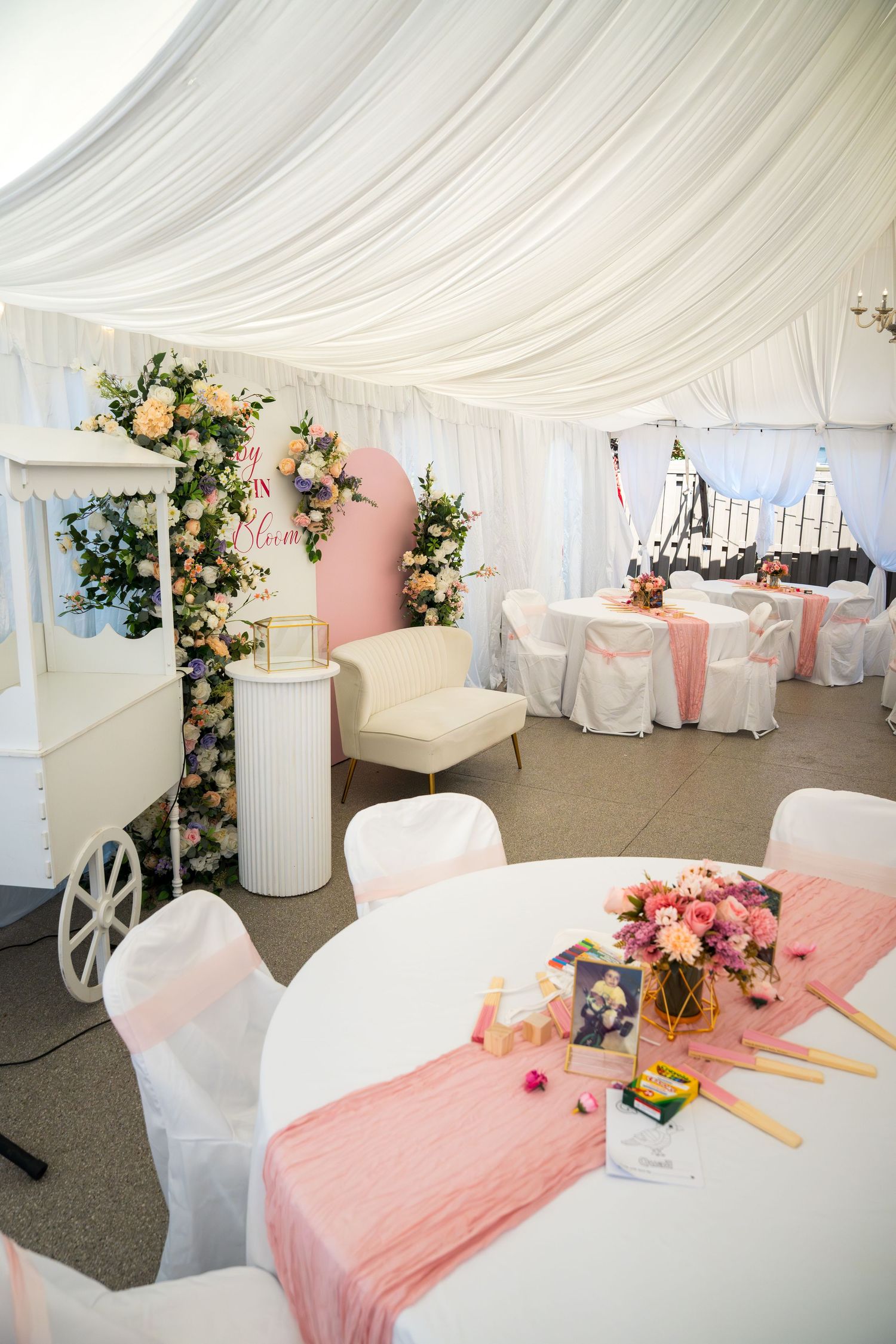 White wedding reception tent with pink table runners and floral decorations.