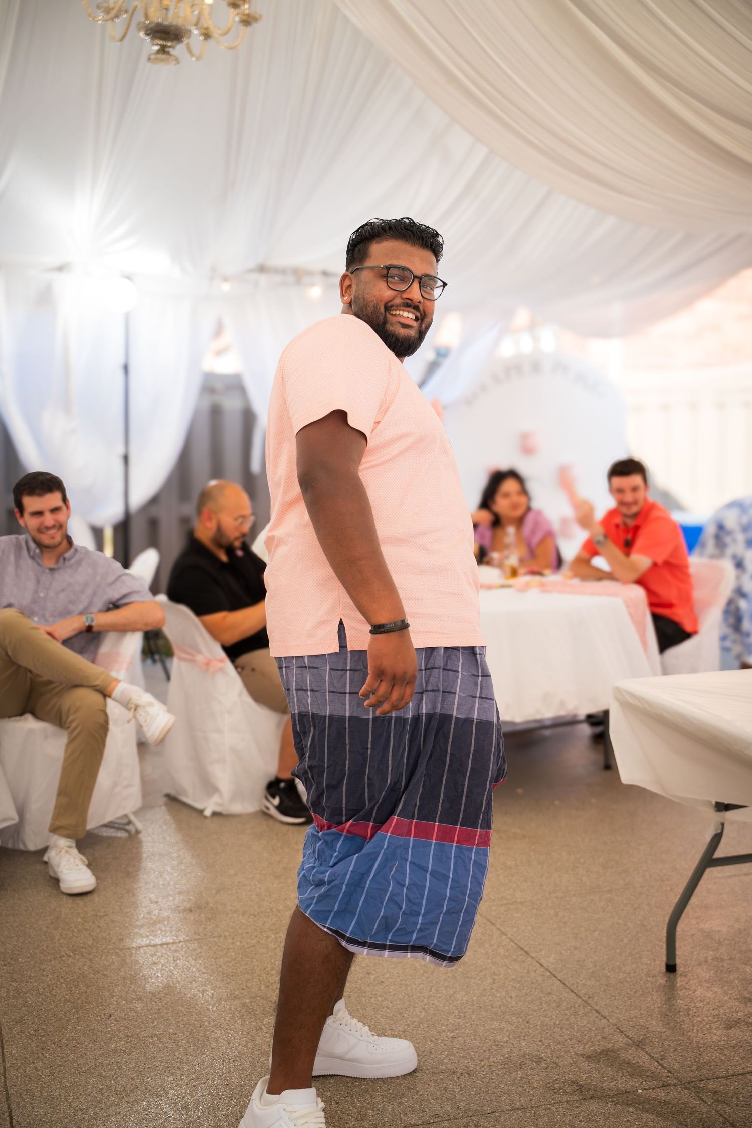 Person in a peach shirt and striped shorts dancing at a celebration event.